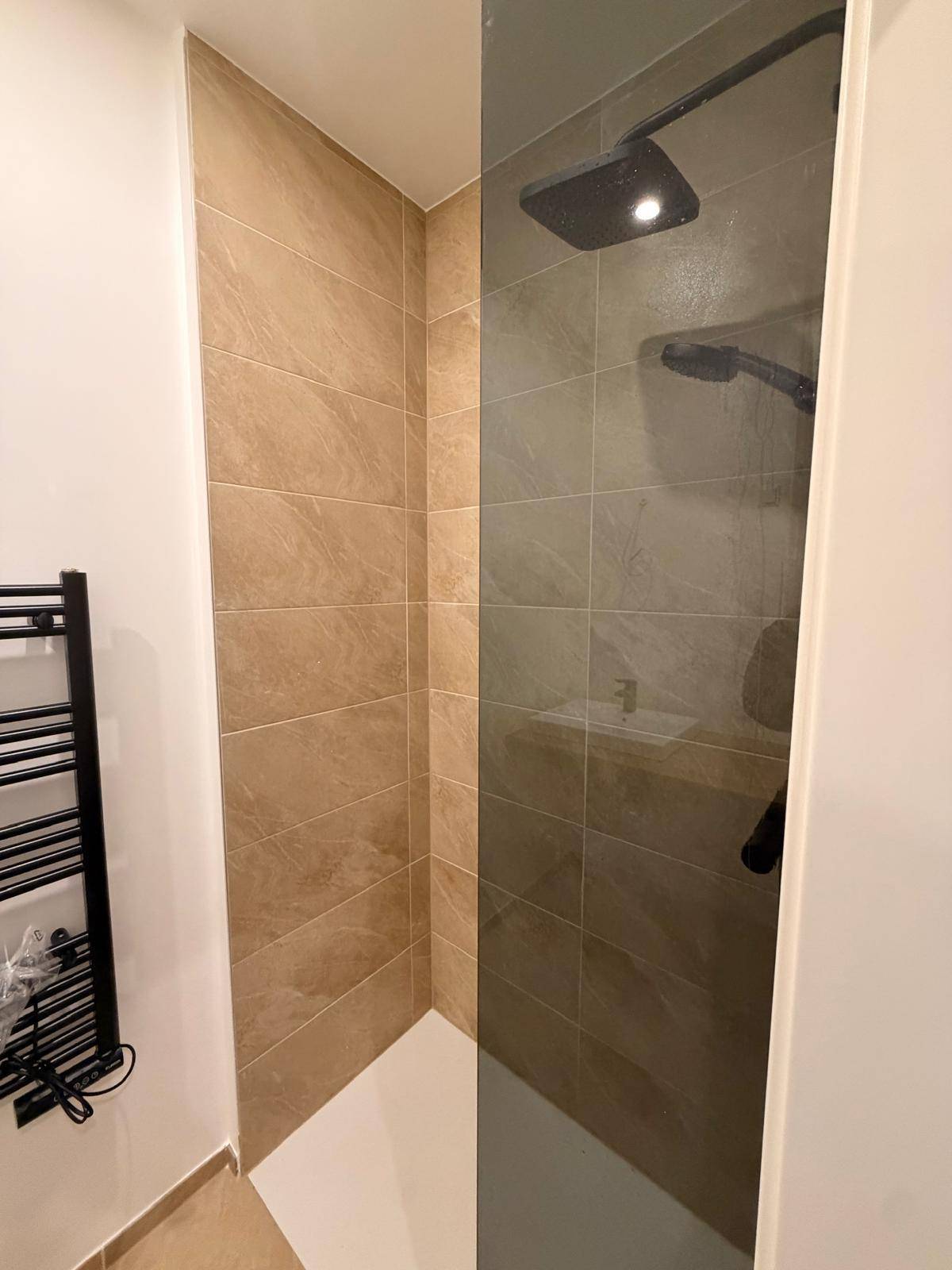 Moderne Duschkabine mit Regendusche, Fliesenwänden und Glasabtrennung im Badezimmer.