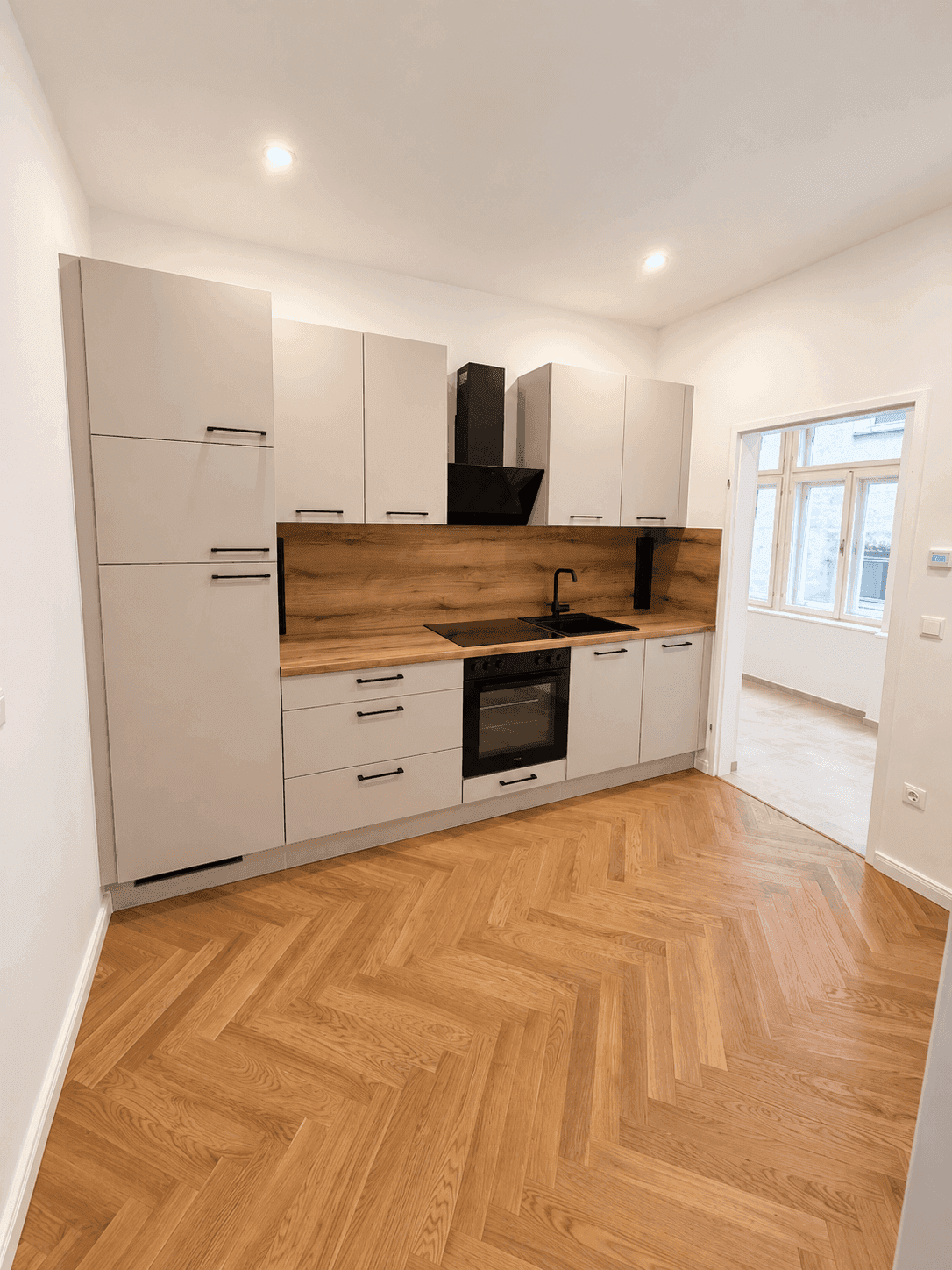 Moderne Einbauküche in Grau mit Holzdetails, Induktionskochfeld und integriertem Backofen.