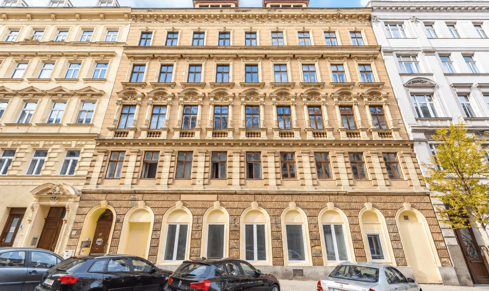 Historische Fassade eines Mehrfamilienhauses mit reich verzierten Fenstern und klassischer Architektur.