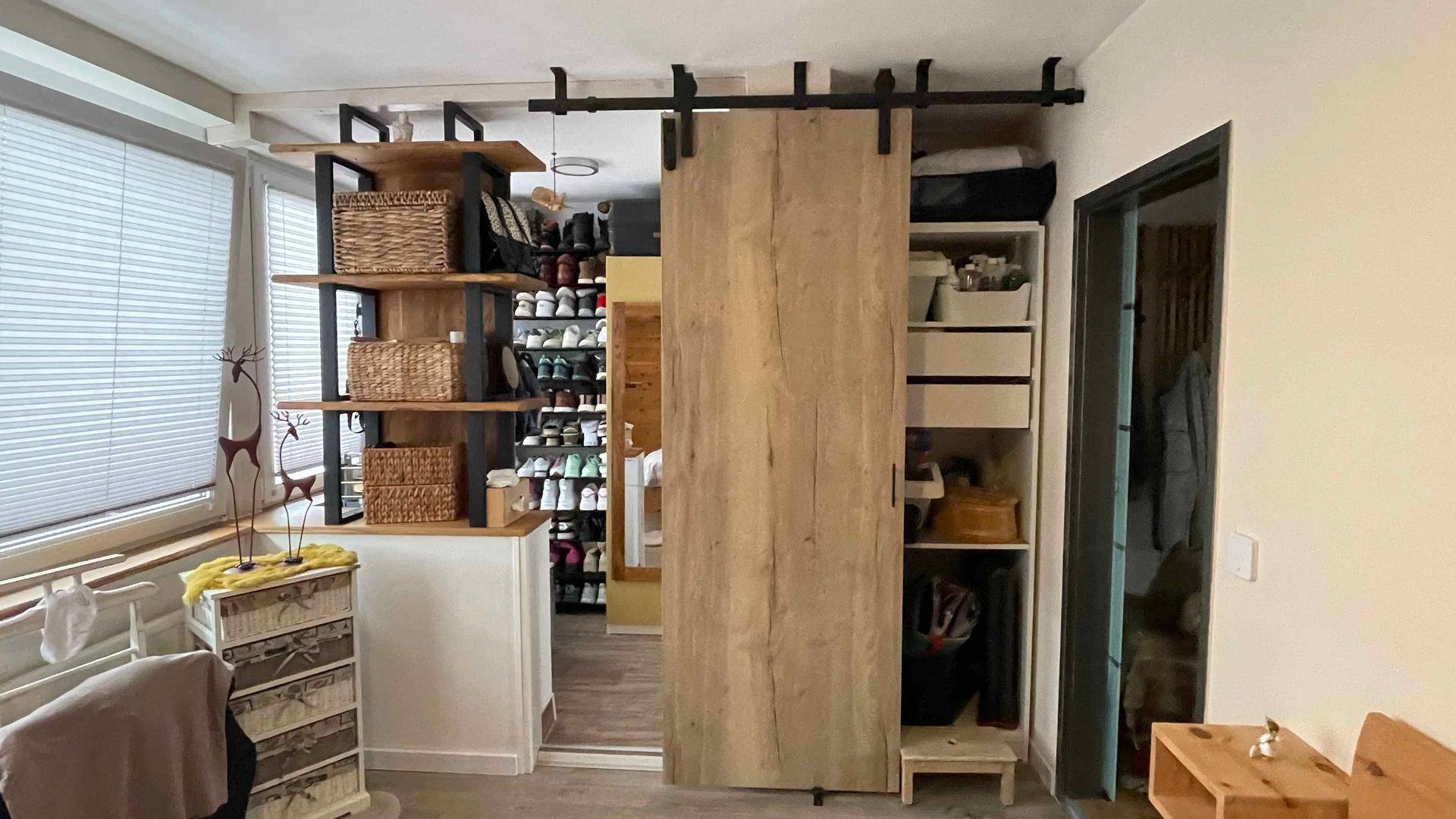 Schlafzimmer mit moderner Schiebetür und Einblick in den begehbaren Kleiderschrank.