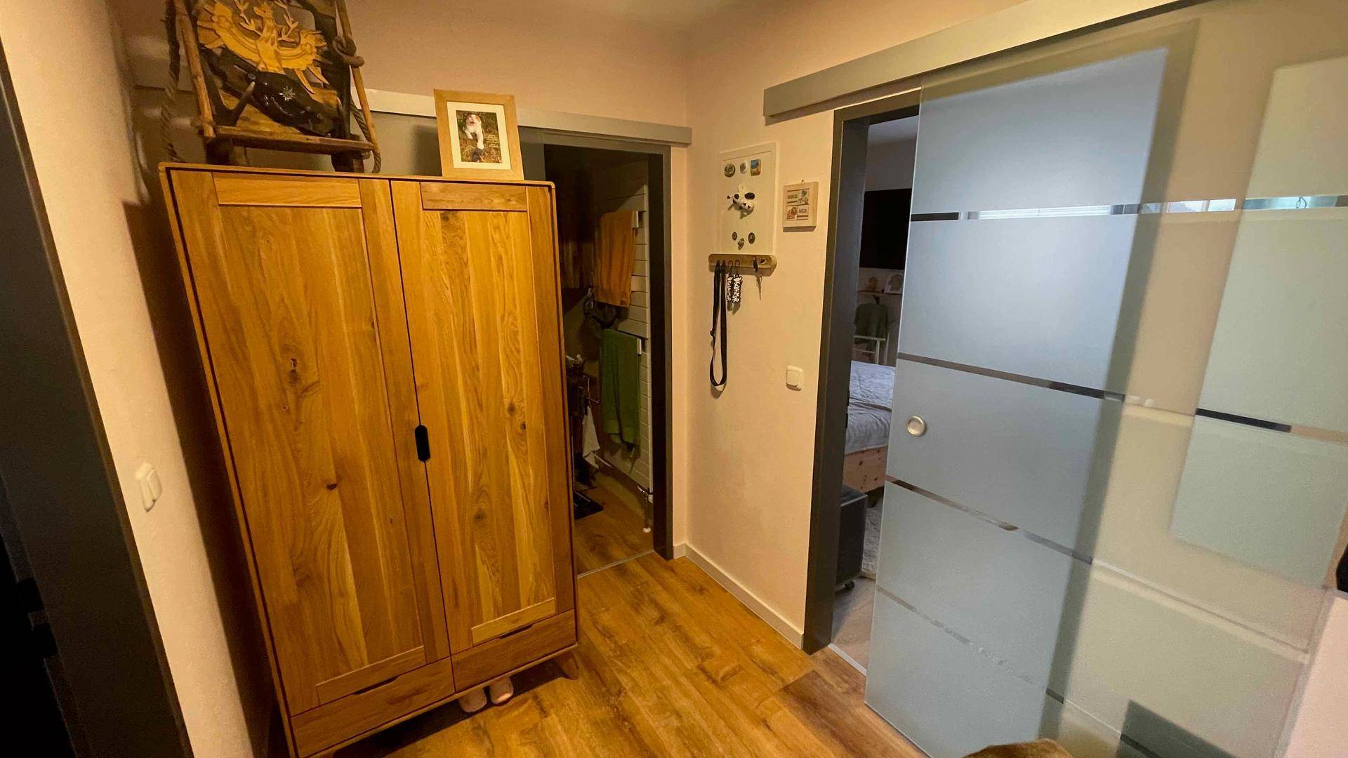 Flur mit Holzschrank und einer modernen Schiebetür aus Milchglas.