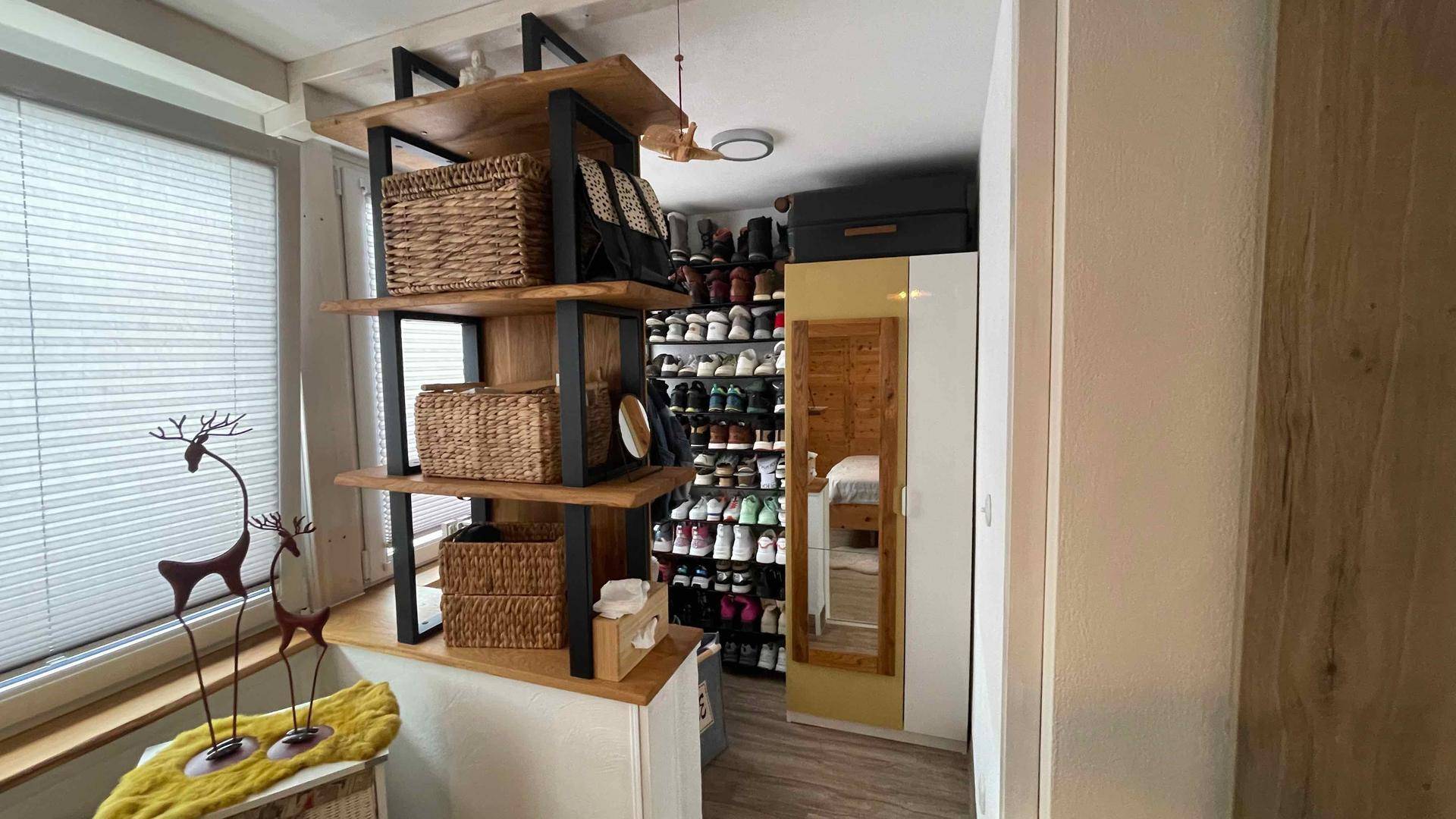 Begehbarer Kleiderschrank mit Regalen für Schuhe und Körben, gut organisiert und hell.
