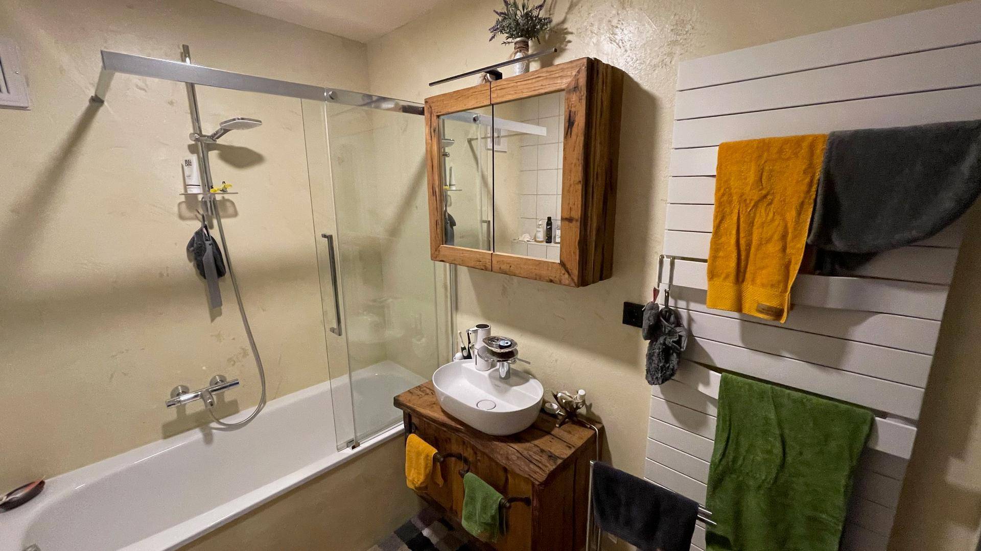 Gemütliches Badezimmer mit Badewanne, Holzelementen und einem beheizten Handtuchhalter.