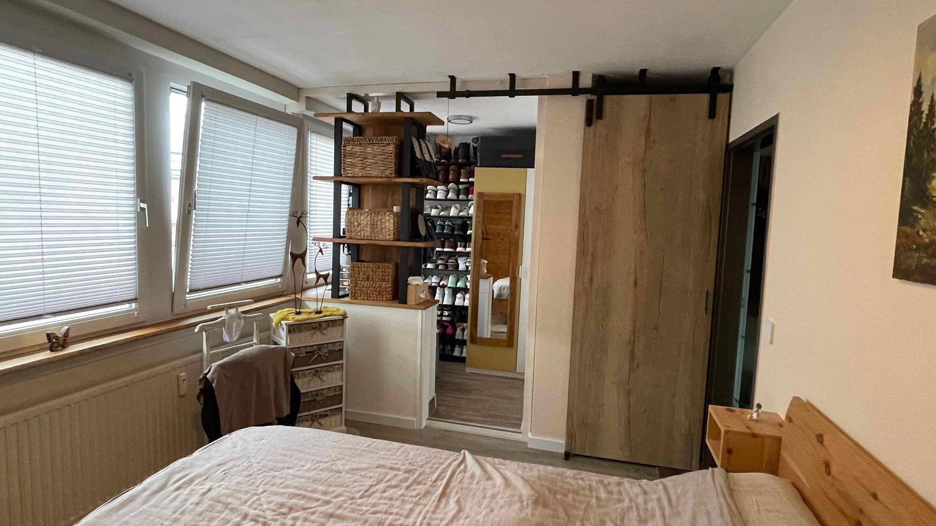 Schlafzimmer mit Schiebetür, die zu einem begehbaren Kleiderschrank führt.