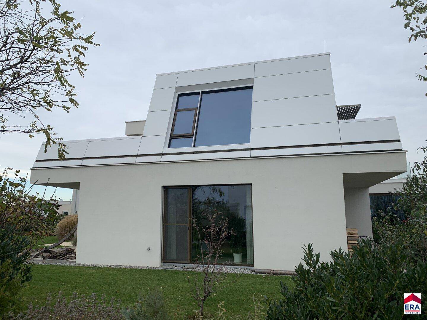 Seitenansicht der modernen Villa mit großen Fenstern und minimalistischer Architektur.