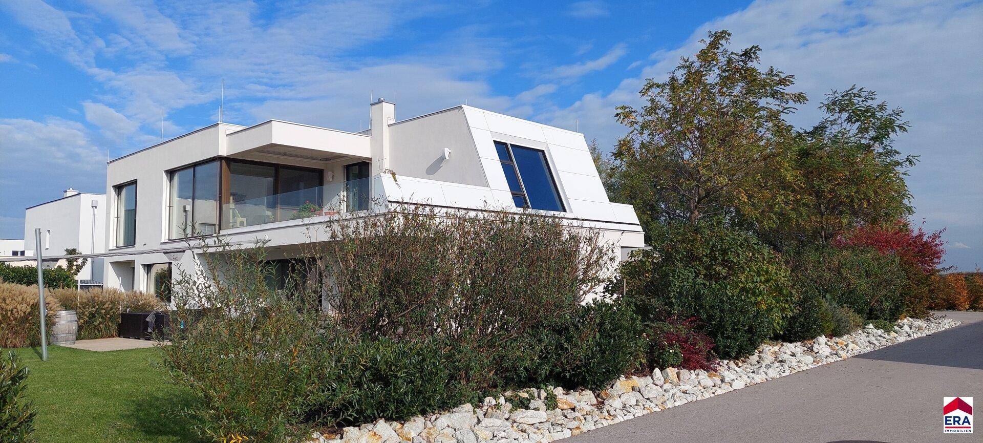 Moderne Hausfassade mit großen Fenstern und einem liebevoll angelegten Steingarten.