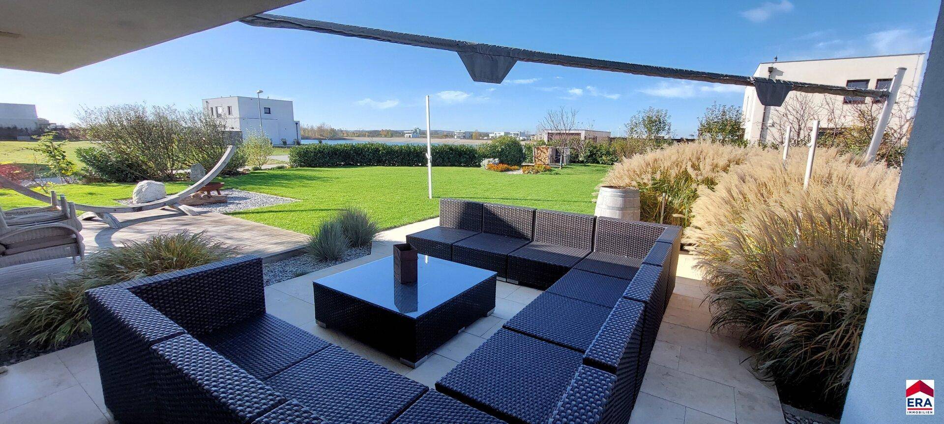 Gemütliche Terrasse mit modernen Loungemöbeln und Blick auf den weitläufigen Garten.