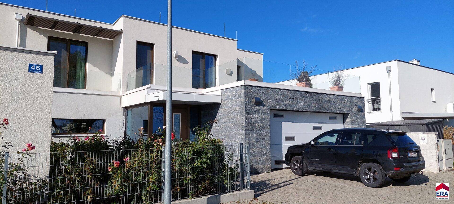 Vorderansicht der modernen Villa mit Garage, Auffahrt und gepflegtem Vorgarten.