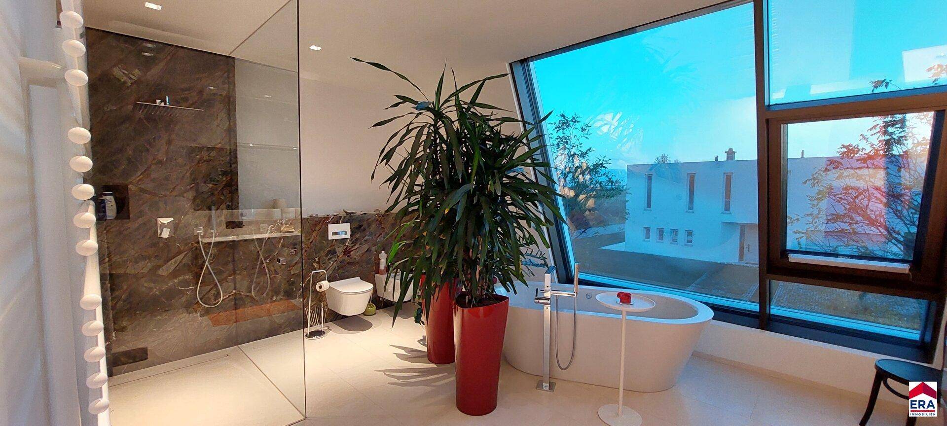Helles Badezimmer mit freistehender Badewanne, großer Dusche und bodentiefen Fenstern.