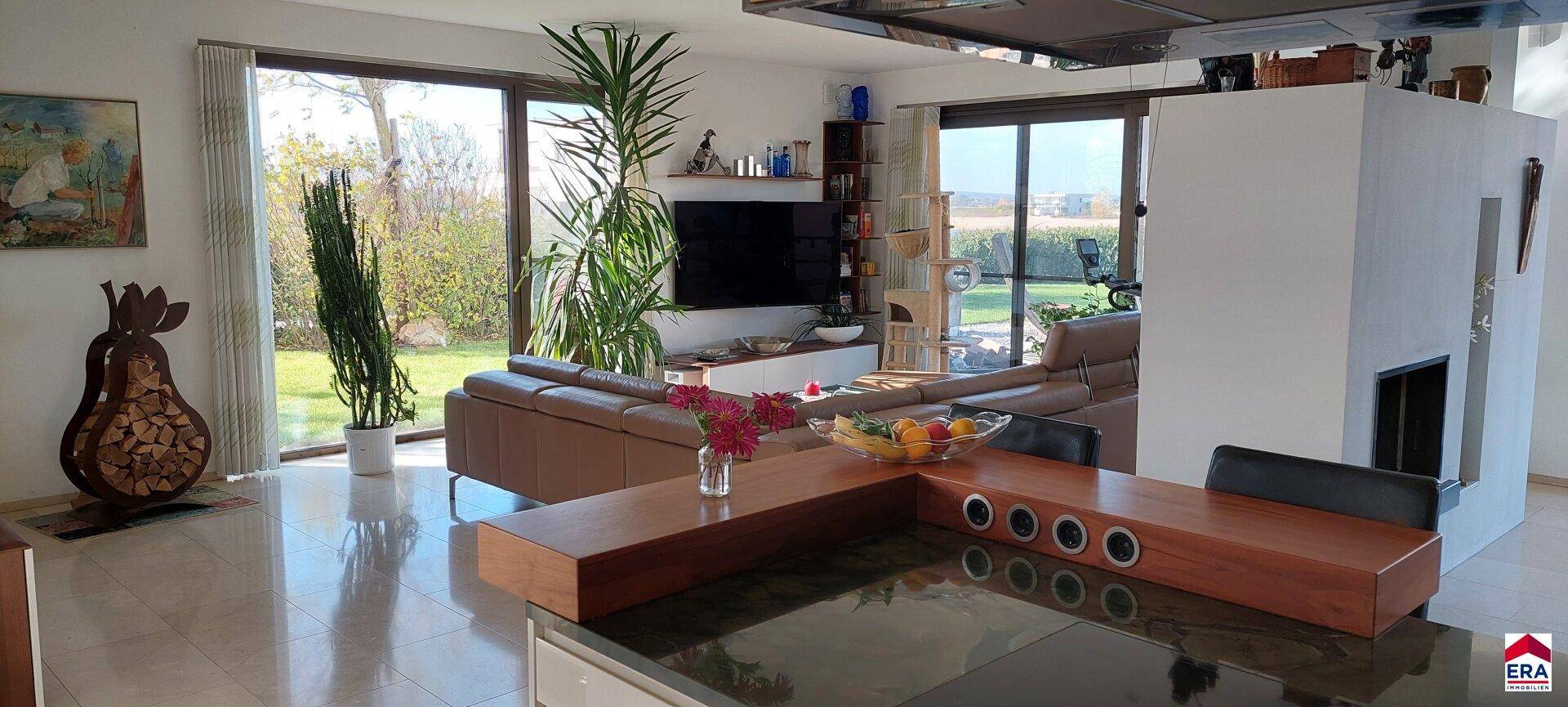 Geräumiger Wohnbereich mit bequemen Sofas, Kamin und großen Fensterfronten zum Garten.