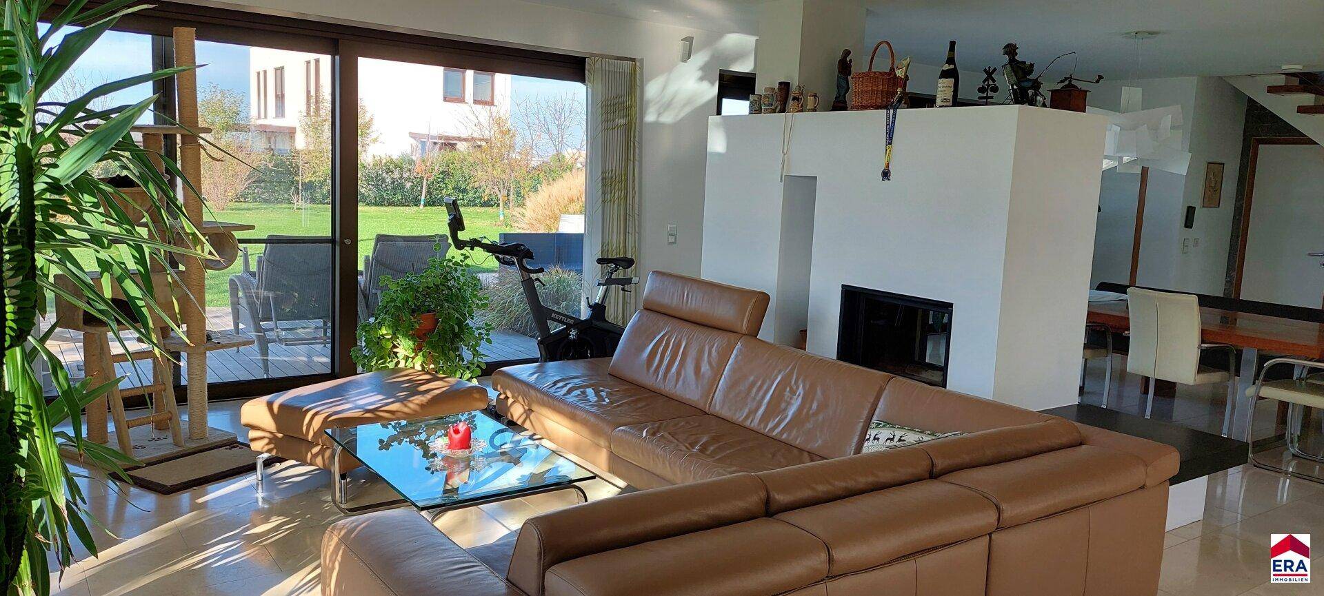 Heller Wohnbereich mit Ledersofa, Couchtisch und Blick auf den Garten.