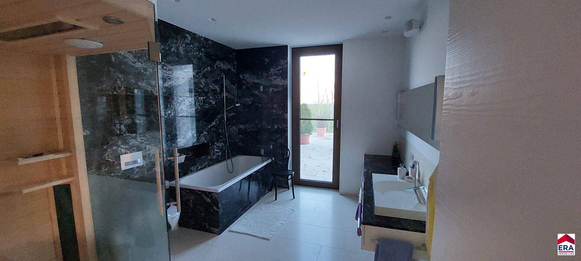 Modernes Badezimmer mit dunklen Marmorfliesen, Badewanne und separater Dusche.