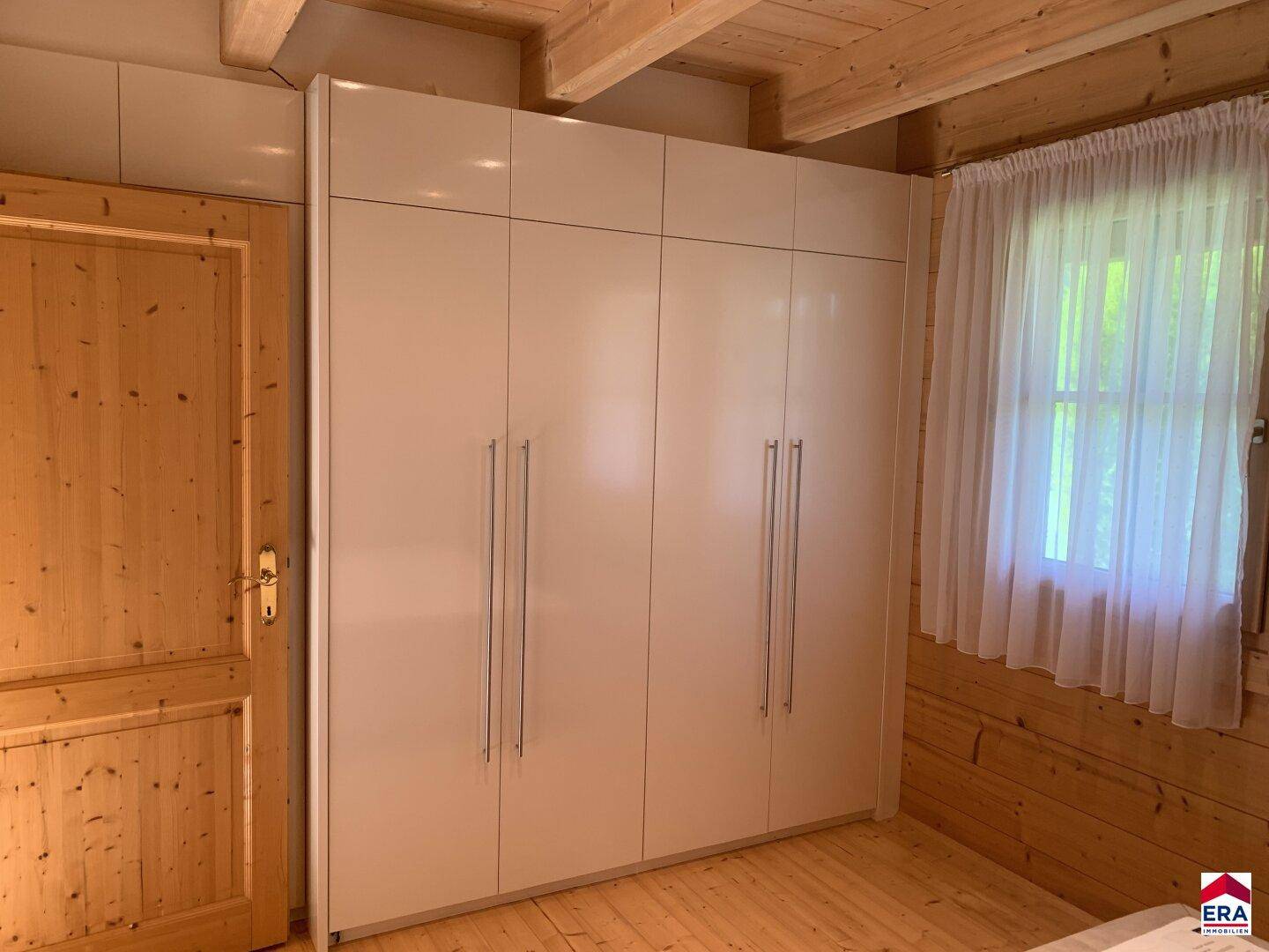 Schlafzimmer mit großem weißen Kleiderschrank und Holzwänden.
