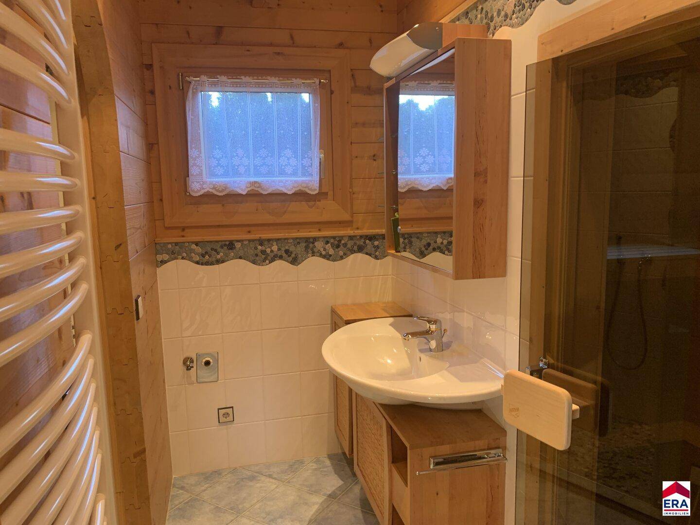 Badezimmer mit Waschbecken, Spiegelschrank und Fenster in Holzwand.