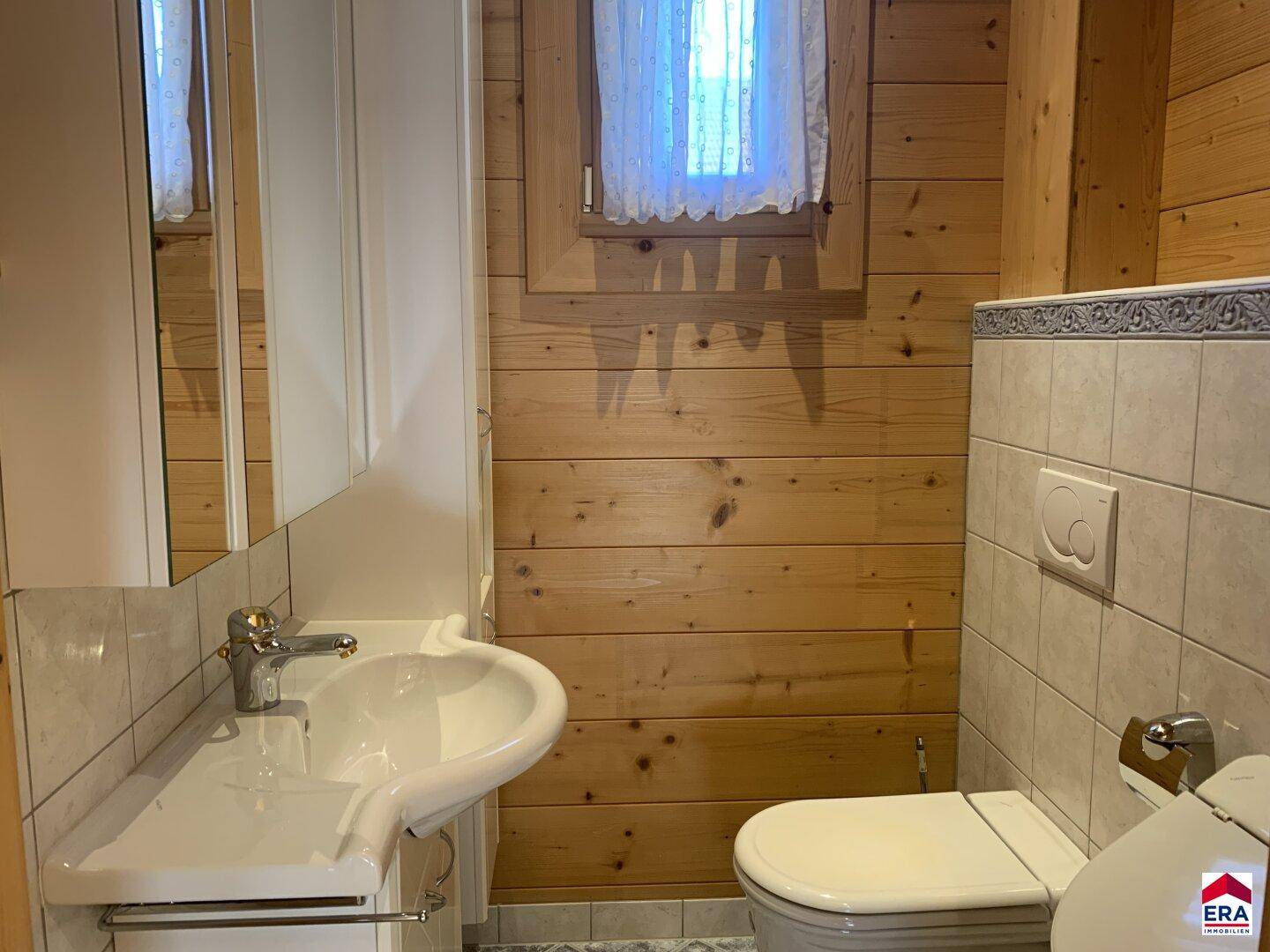 Separates WC mit Waschbecken, Toilette und Fliesenboden.