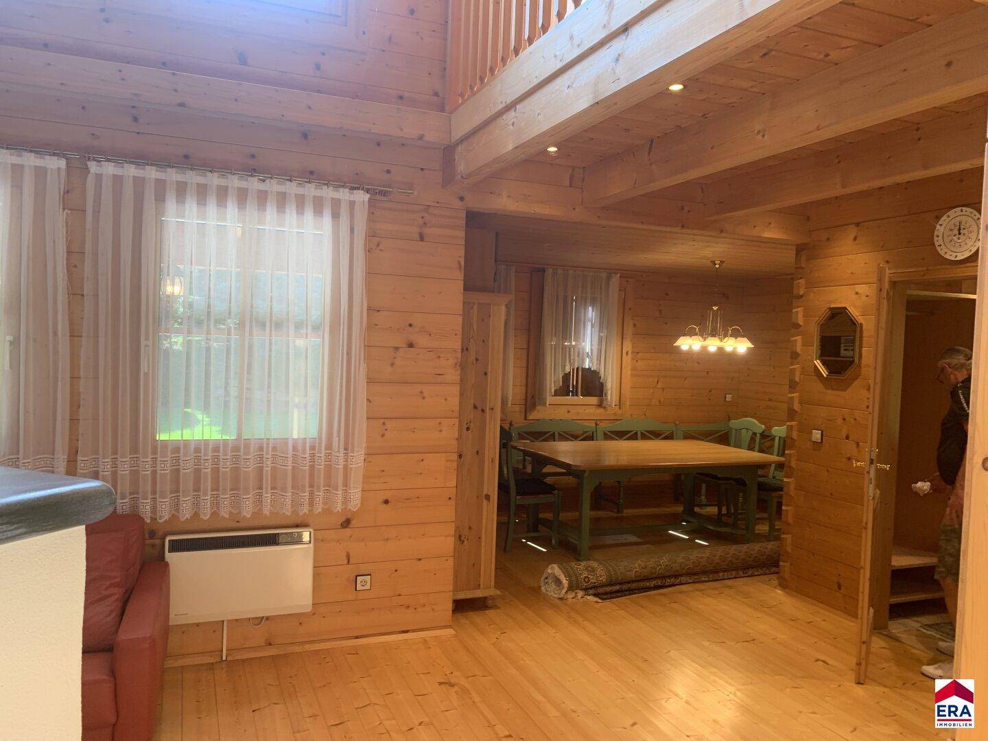 Geräumiger Wohn- und Essbereich mit Holzboden und Blick auf die Küche.