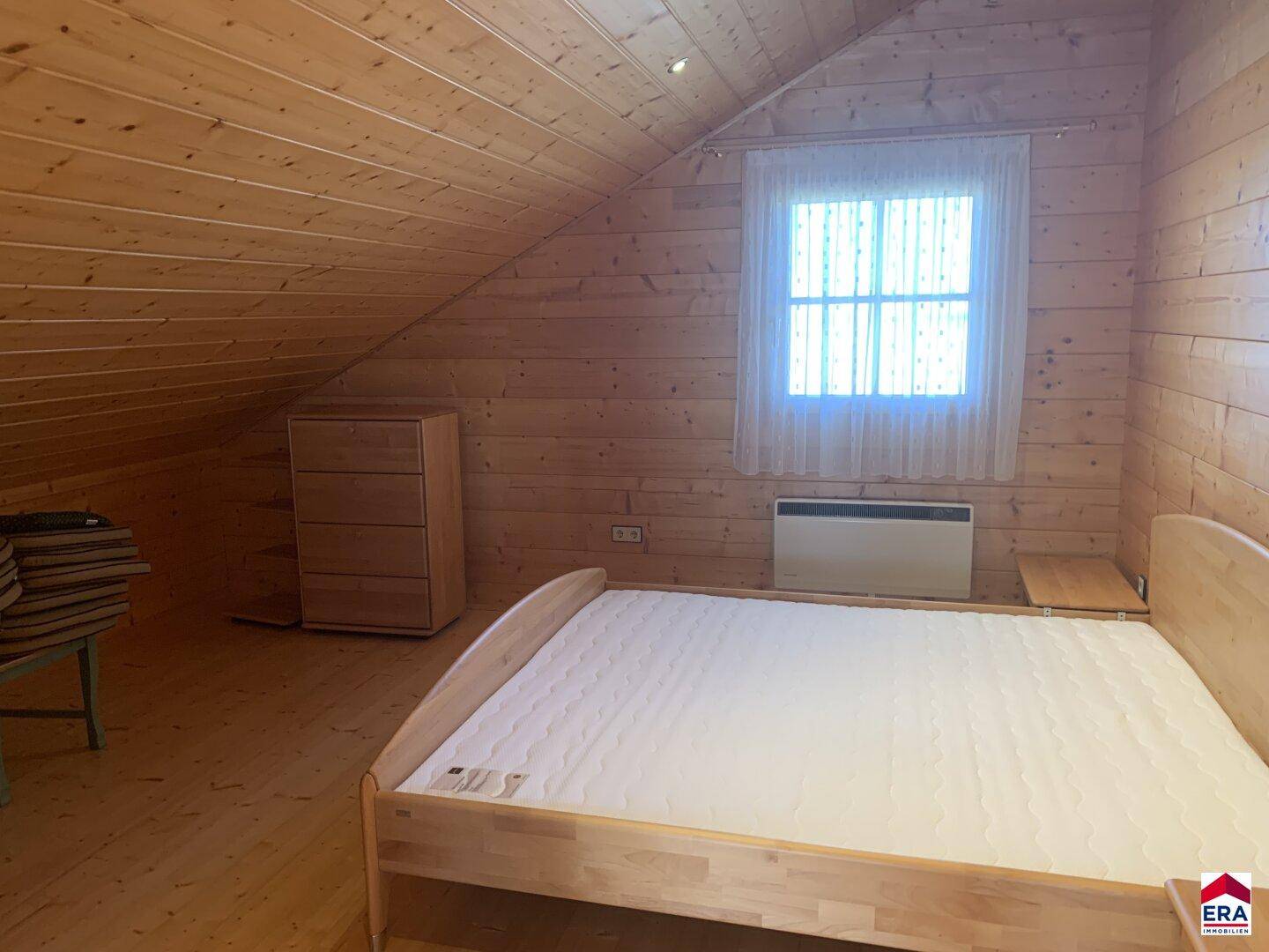 Gemütliches Schlafzimmer im Dachgeschoss mit Holzbett und Holzwänden.