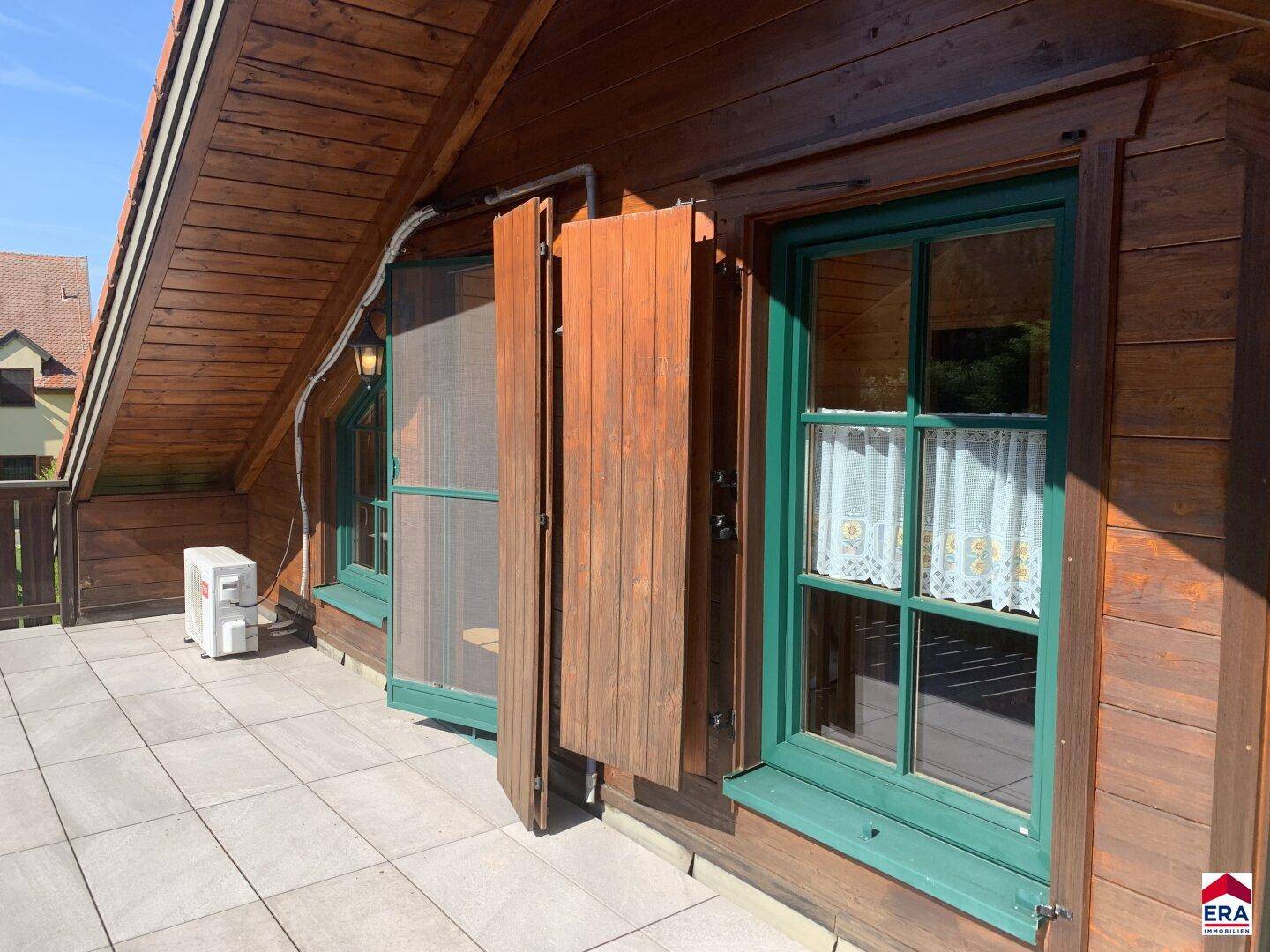 Balkon mit Fliesenboden, Holzfassade und Klimaanlage.