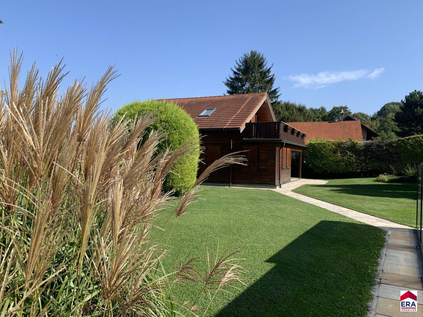 Gepflegter Garten mit Ziergräsern und Blick auf das charmante Holzhaus.