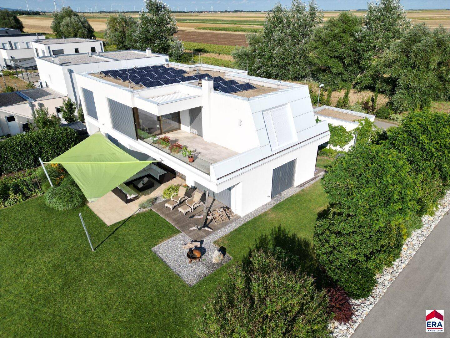 Moderne Villa mit Flachdach, Photovoltaikanlage, großem Garten, Terrasse und Blick ins Grüne.