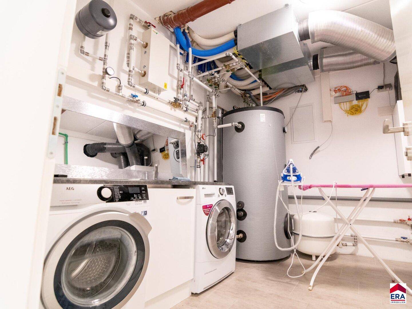 Praktischer Hauswirtschaftsraum mit Waschmaschine, Trockner und Heizungsanlage.