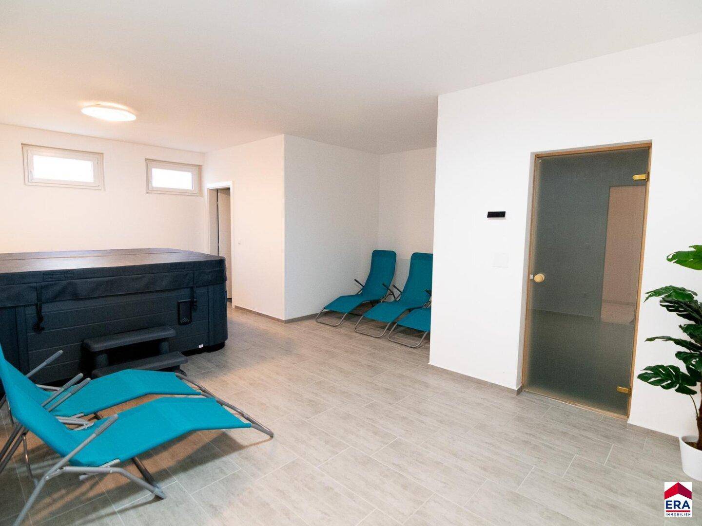 Entspannungsbereich mit Whirlpool, Liegestühlen und Zugang zu einer Sauna oder Dampfbad.