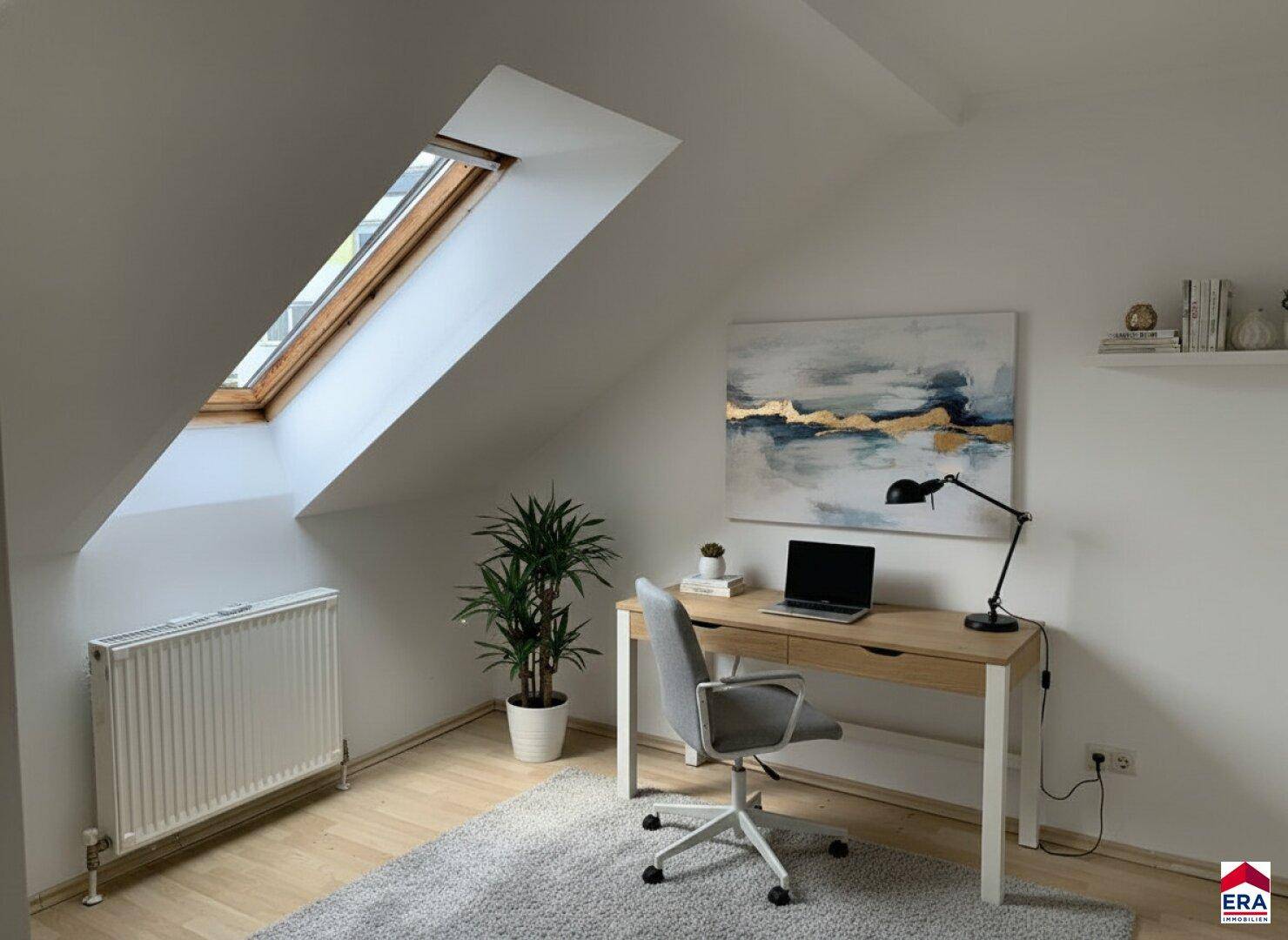Helles Arbeitszimmer im Dachgeschoss mit Schreibtisch, Bürostuhl und einem großen Dachfenster.