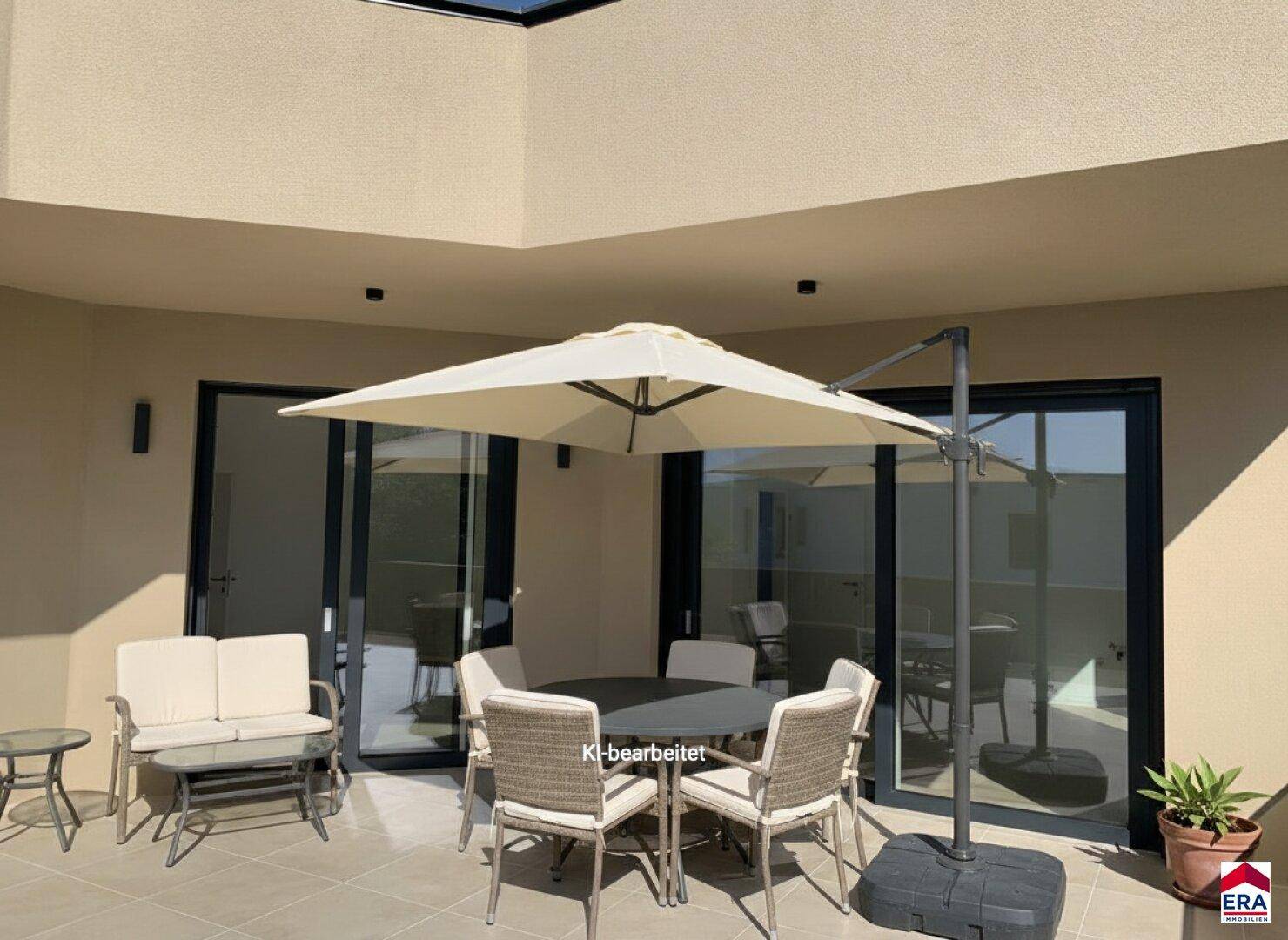 Möblierte Terrasse mit Sonnenschirm und bequemen Sitzgelegenheiten, ideal für entspannte Stunden im Freien.