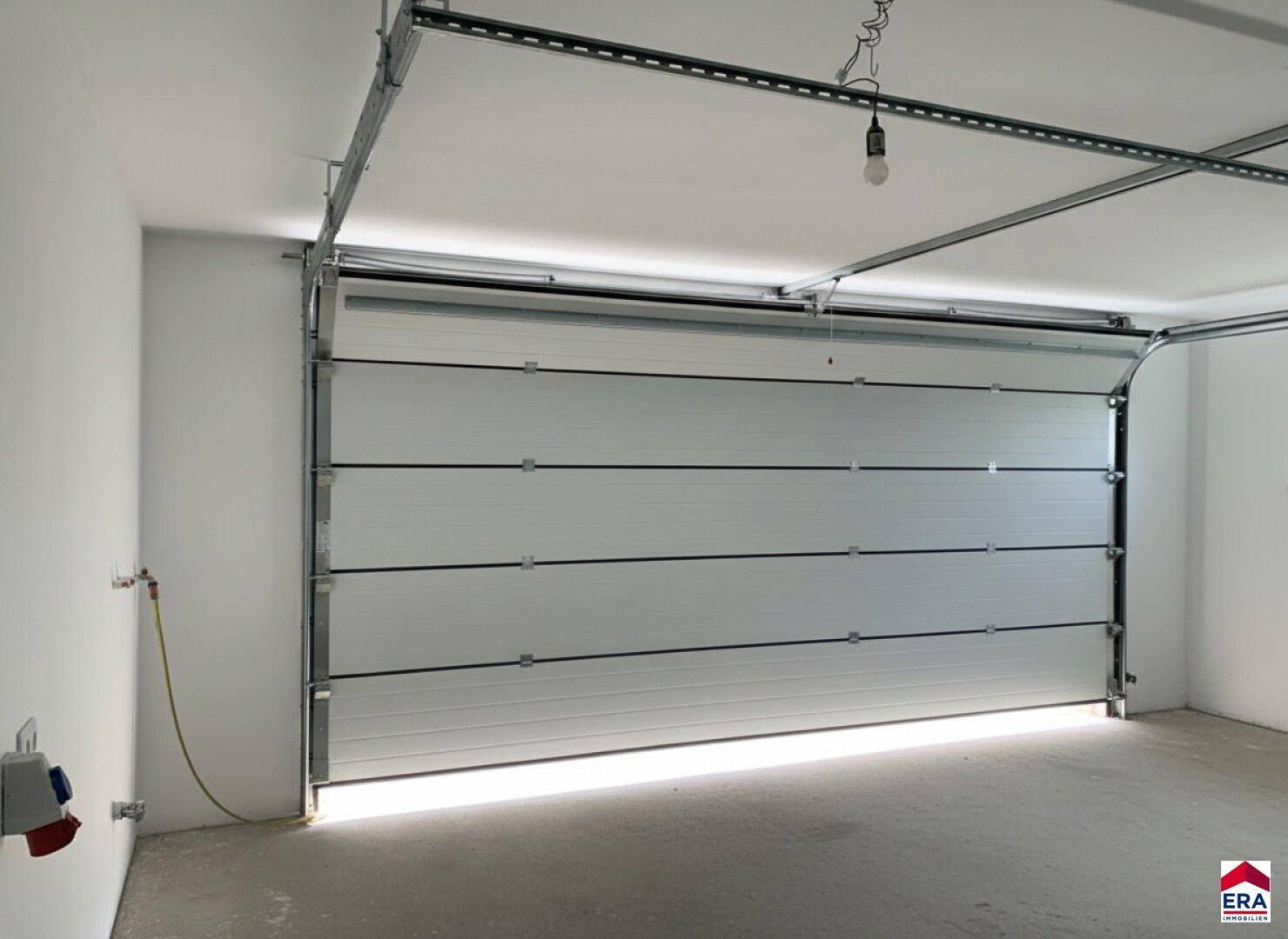 Geräumige und helle Garage mit Sektionaltor und Betonboden, bereit zur Nutzung.