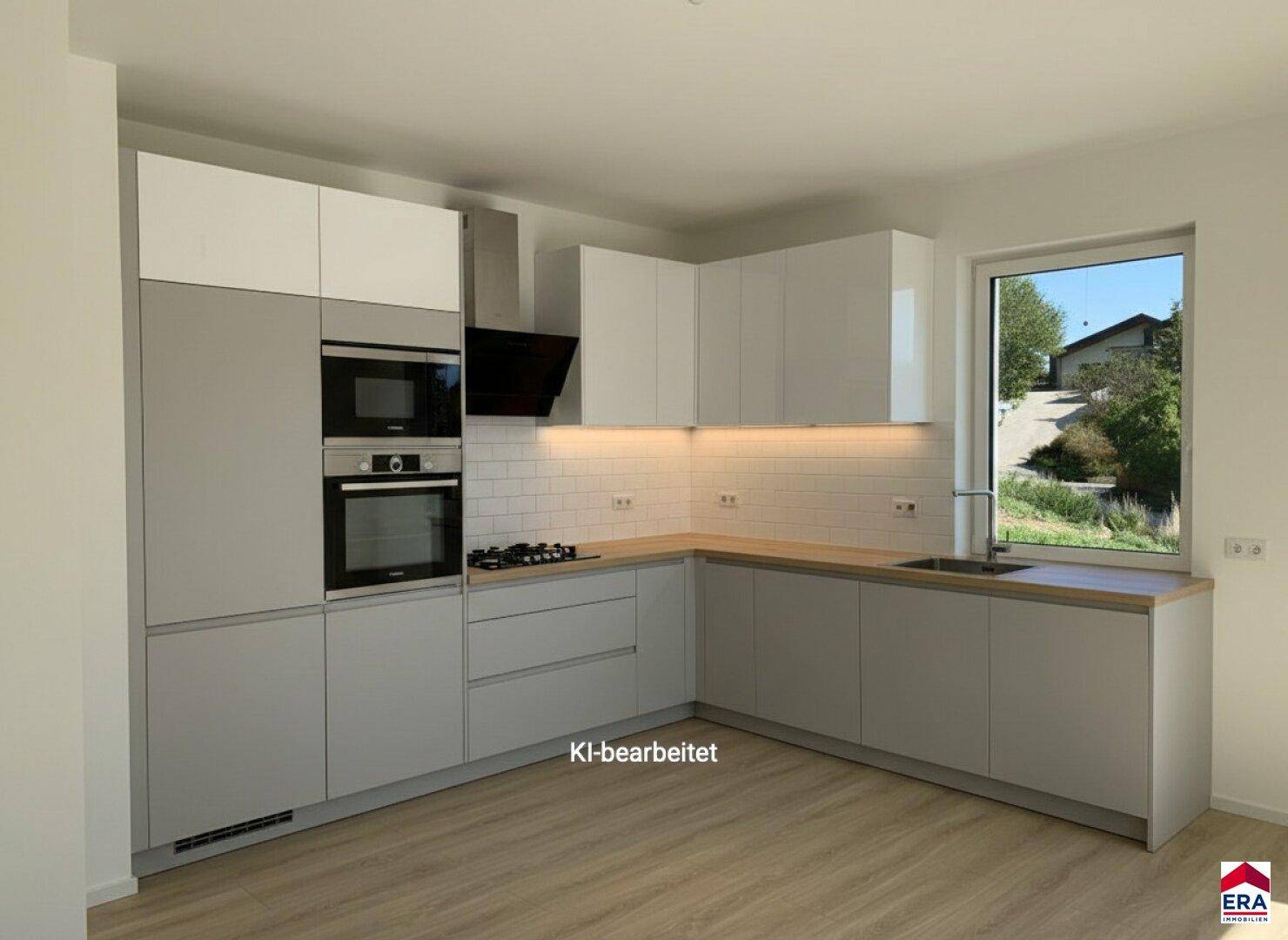 Moderne Einbauküche mit grauen und weißen Schränken, integrierten Geräten und Fenster.