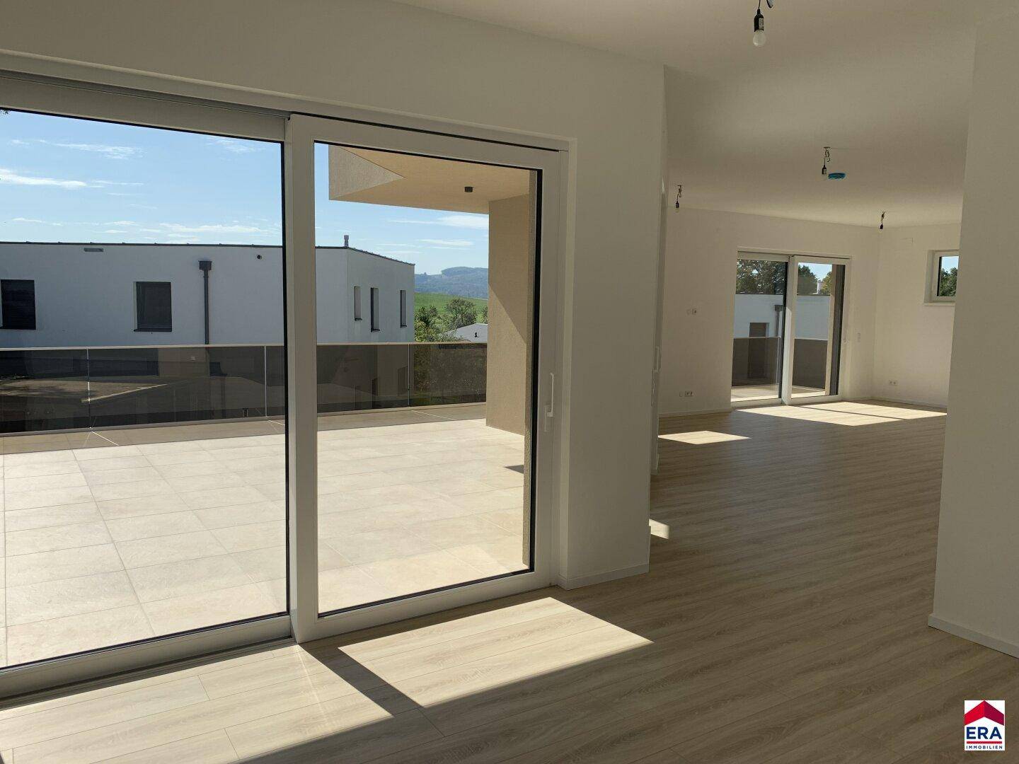 Heller, offener Wohnbereich mit Laminatboden, großen Schiebetüren und direktem Zugang zur Terrasse.