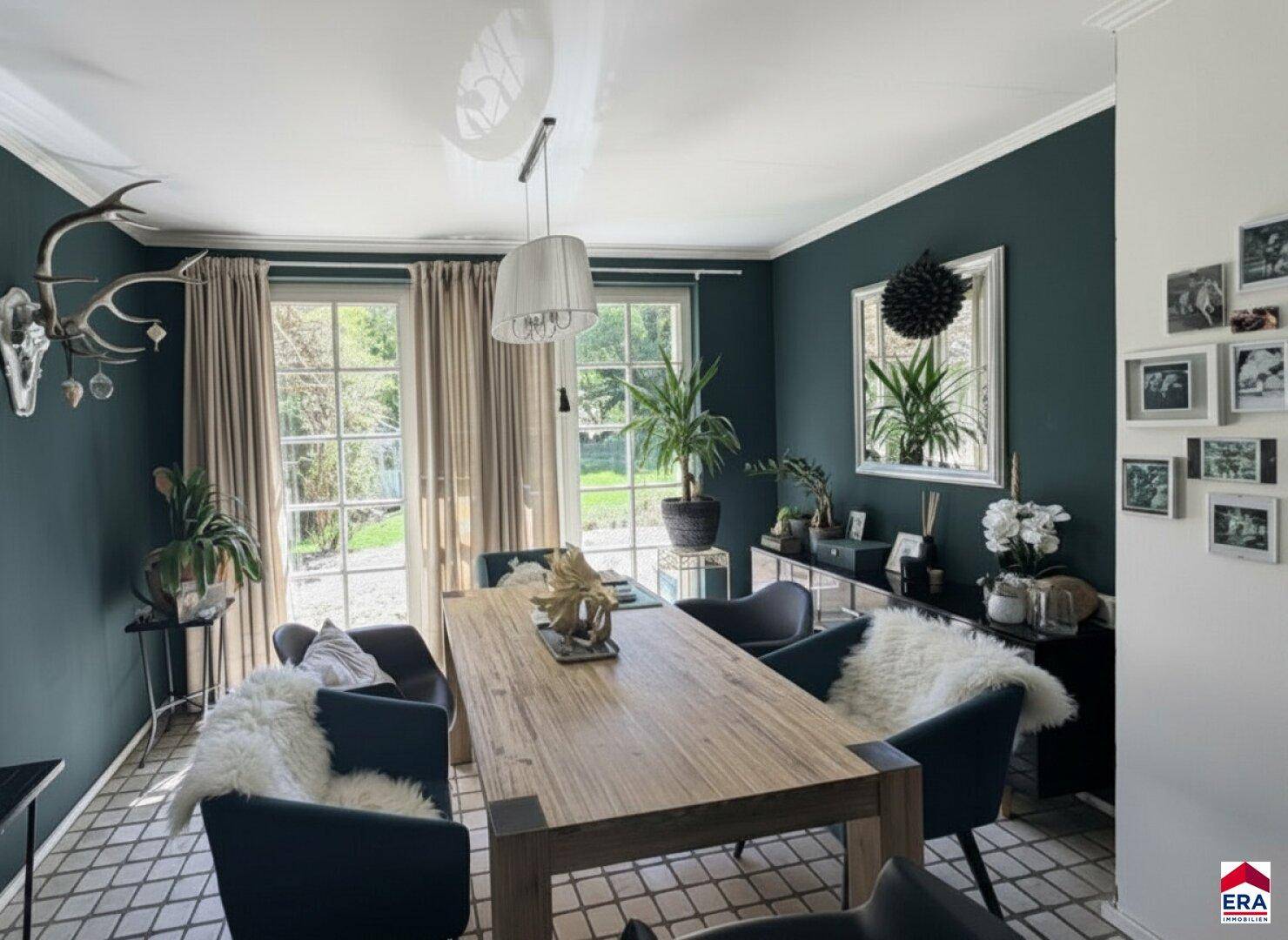 Elegantes Esszimmer mit großem Holztisch, dunklen Wänden und Zugang zum Garten.