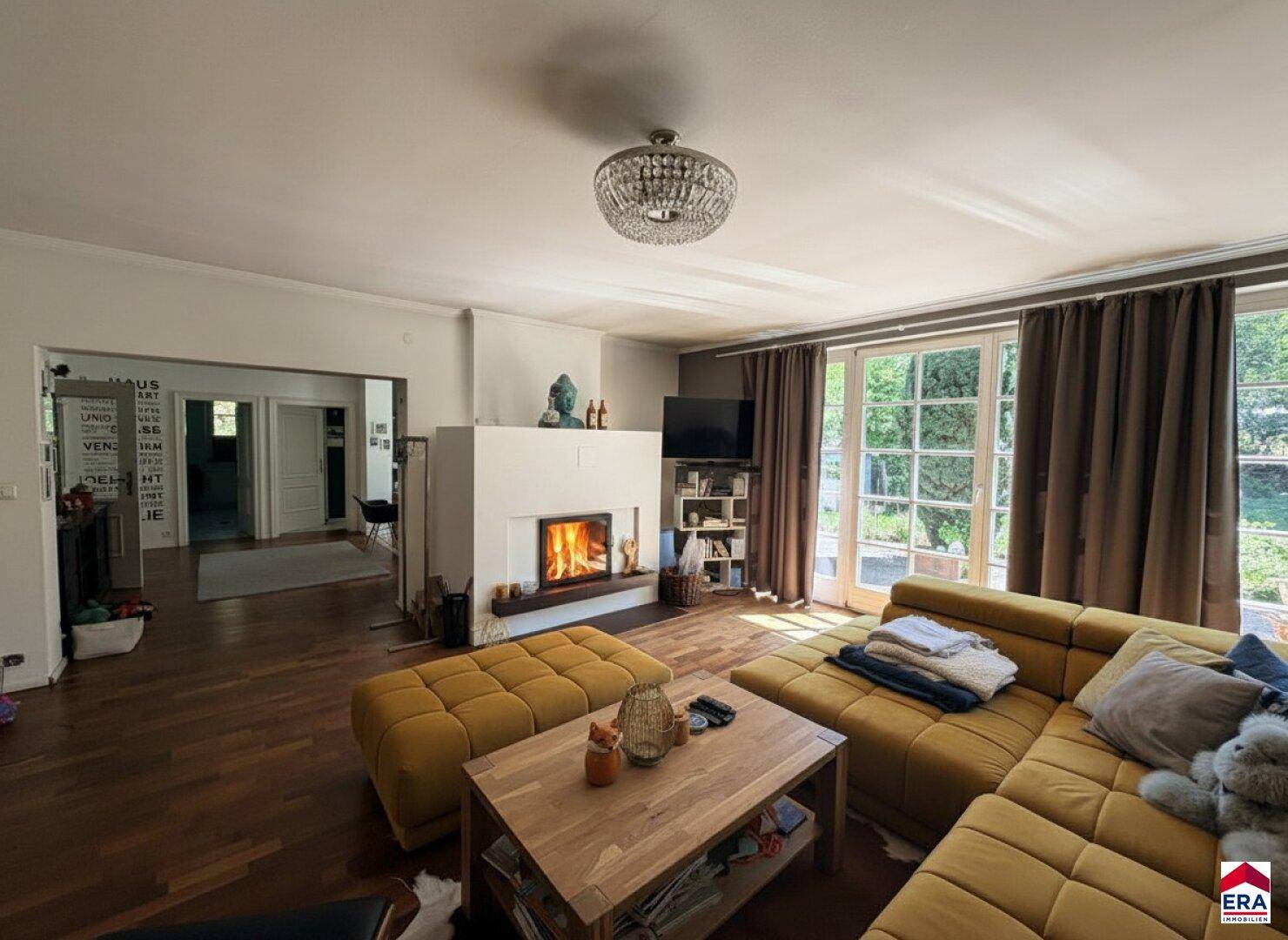 Geräumiges Wohnzimmer mit Kamin, gemütlicher Sitzecke und Zugang zum Außenbereich.