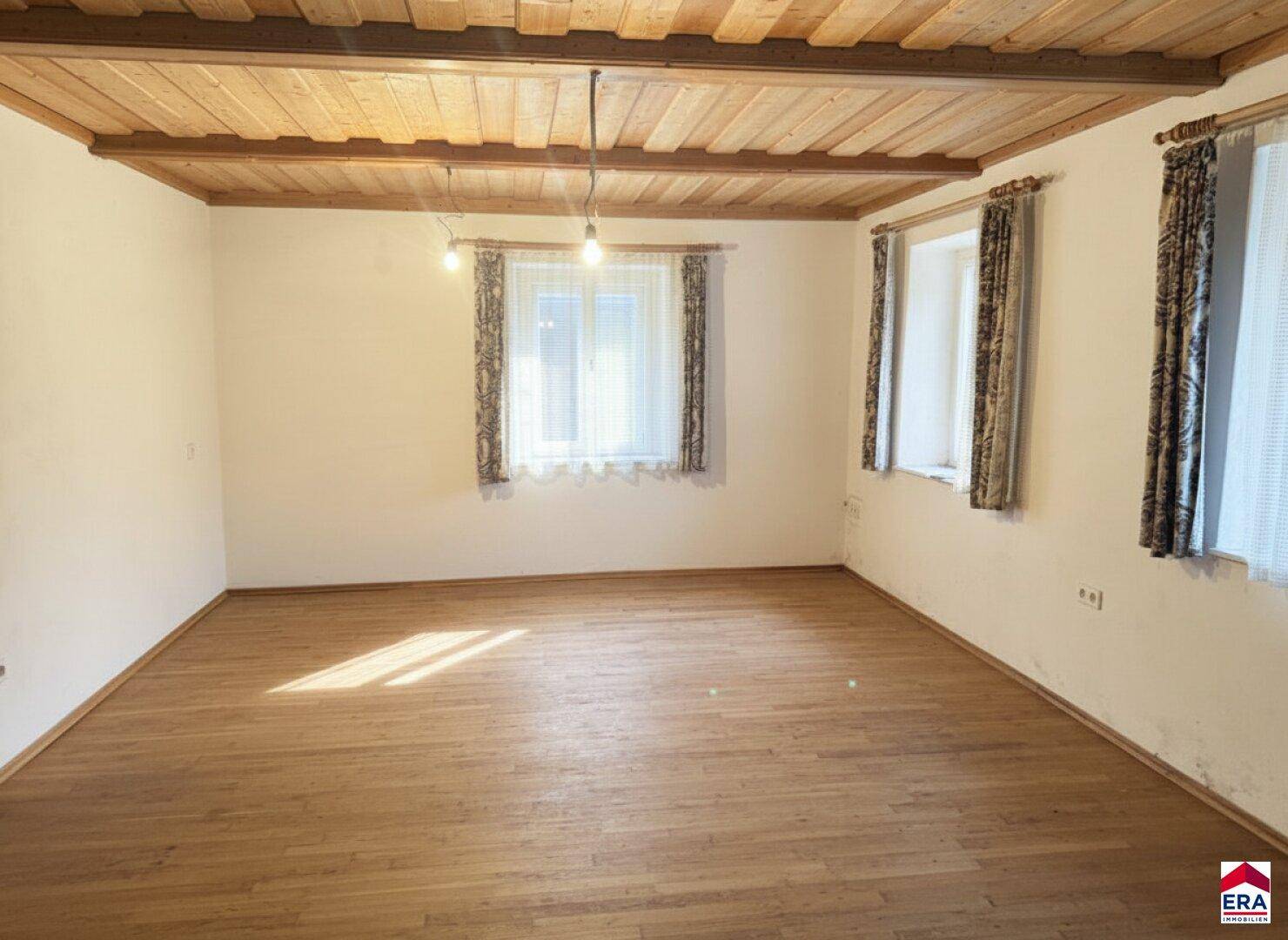 Heller Raum mit Holzbalkendecke und Dielenboden, bereit zur individuellen Gestaltung.