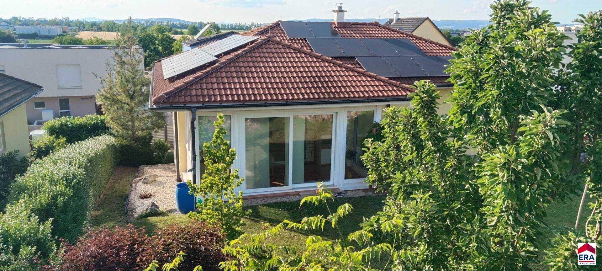 Luftaufnahme des Hauses mit Photovoltaikanlage, Garten und umliegender Bebauung.