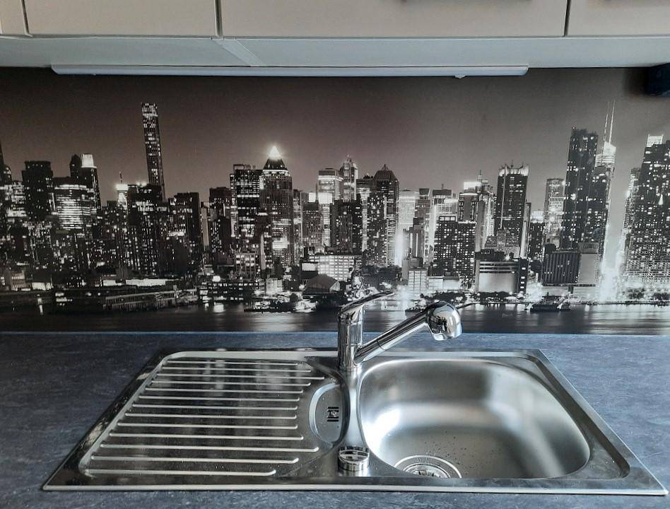 Detailansicht der Küchenspüle mit Armatur und der modernen Skyline-Rückwand.