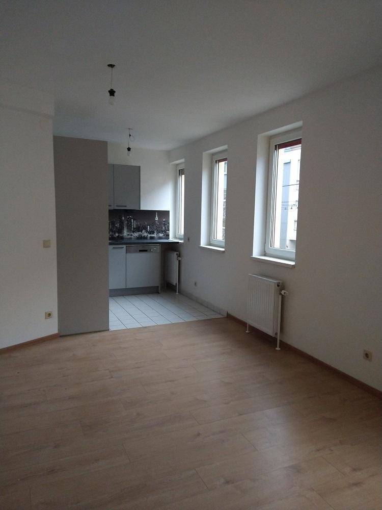 Geräumiger Wohnbereich mit Laminatboden und offener Küchenzeile im Hintergrund.