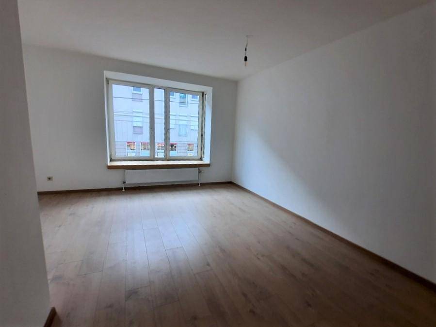 Helles Schlafzimmer mit Laminatboden und einem großen Fenster mit Blick nach draußen.