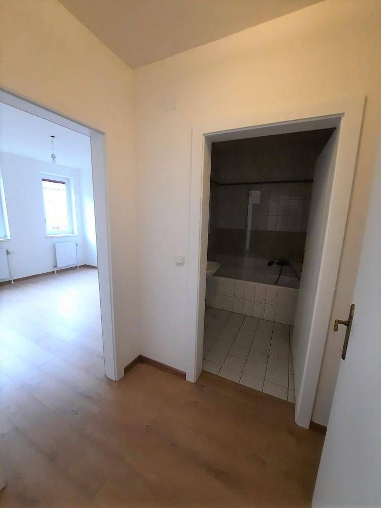Flur mit Laminatboden, der zum Badezimmer und einem weiteren Zimmer führt.