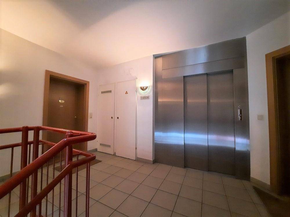 Gemeinschaftlicher Flur mit Aufzug und Treppenhaus in einem Mehrfamilienhaus.