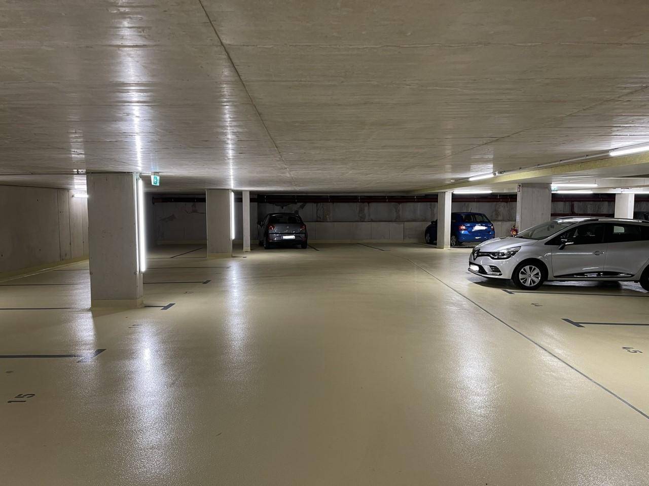 Helle und saubere Tiefgarage mit markierten Stellplätzen und moderner Beleuchtung.
