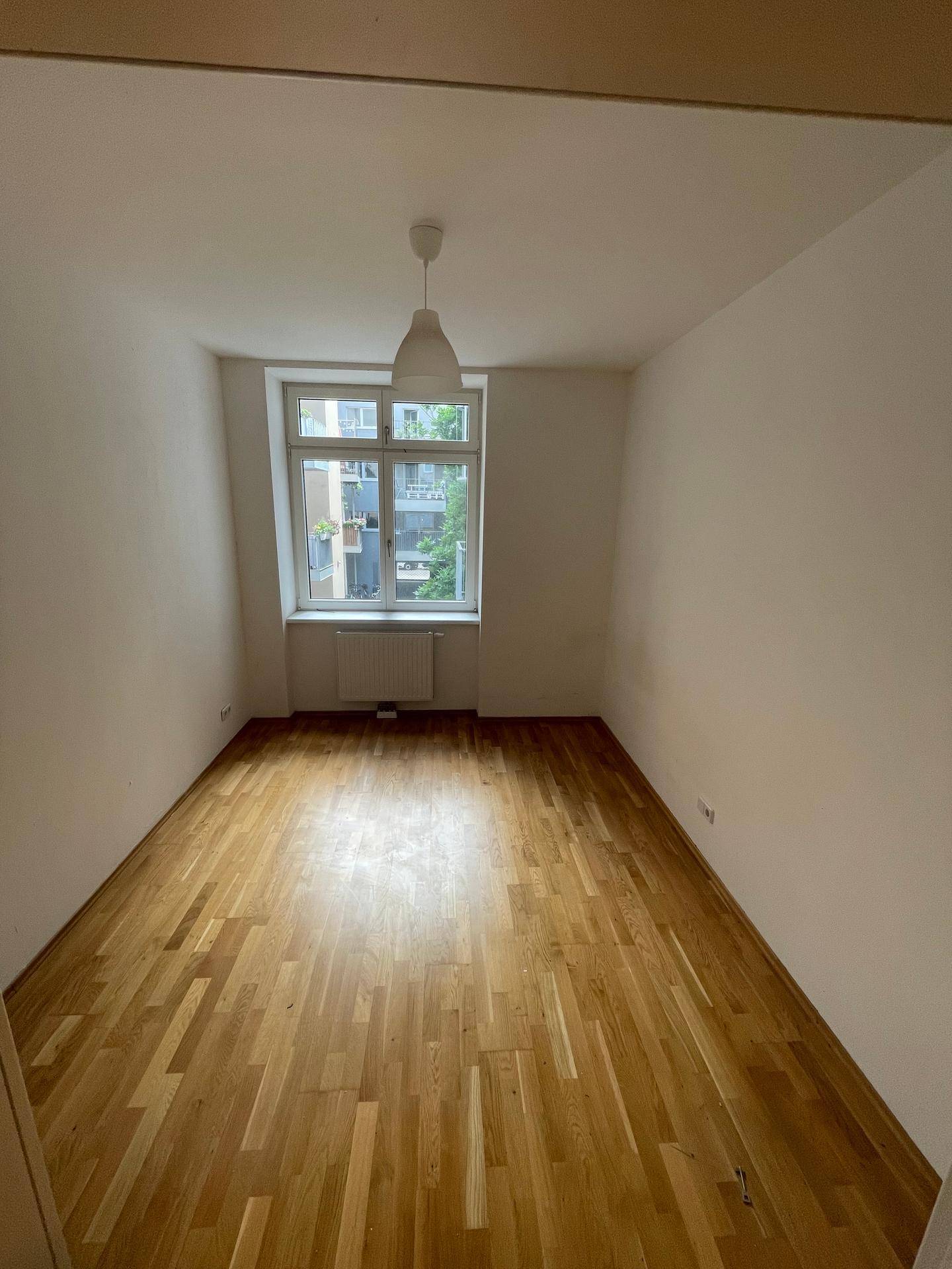 Geräumiges Zimmer mit Parkettboden und Blick ins Grüne, vielseitig nutzbar.