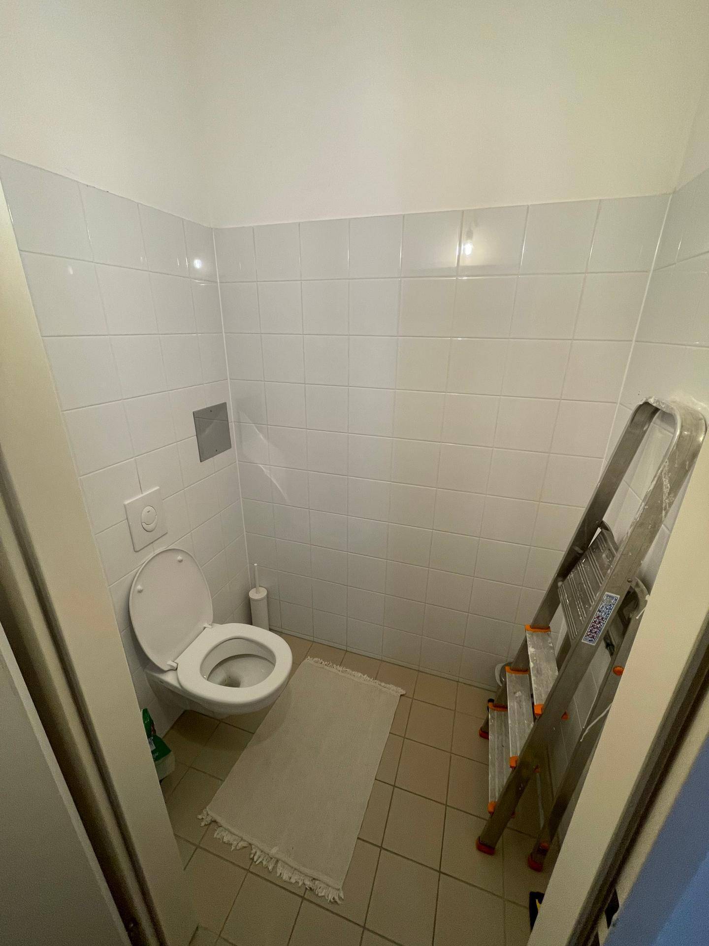 Kleines Gäste-WC mit weißen Fliesen und einfacher Ausstattung.