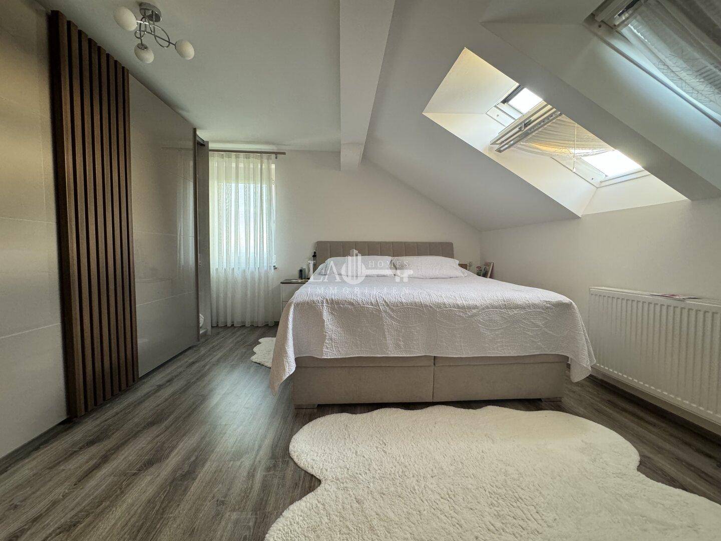 Geräumiges Schlafzimmer im Dachgeschoss mit Doppelbett, Einbauschränken und Dachfenstern.
