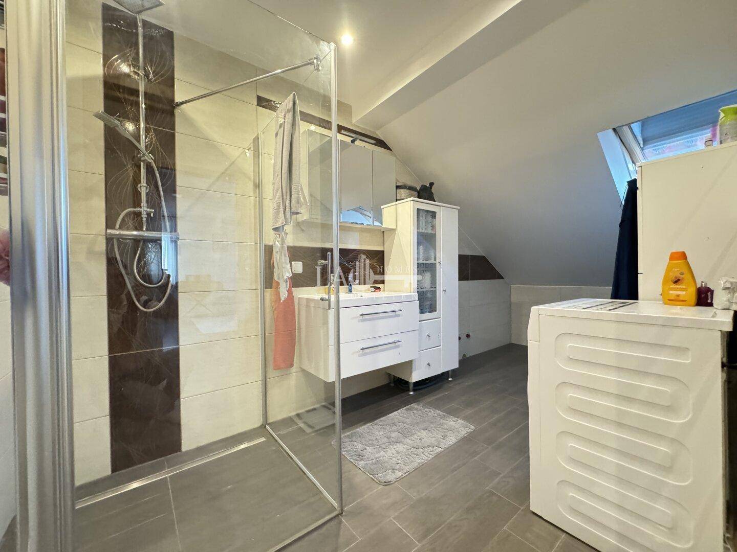 Modernes Badezimmer im Dachgeschoss mit begehbarer Dusche, Waschbecken und Waschmaschine.