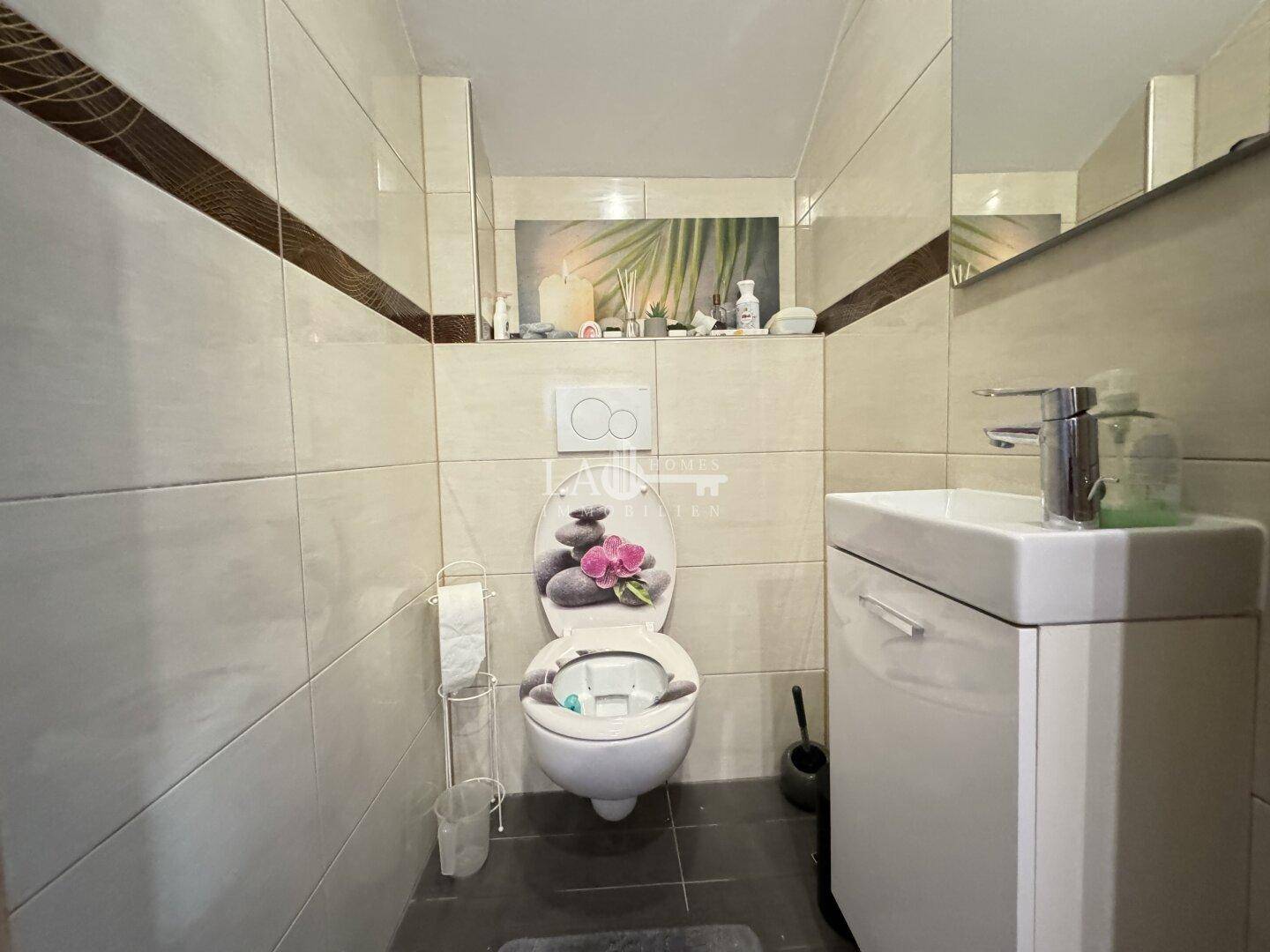 Separates WC im Dachgeschoss mit wandhängendem WC, Waschbecken und Fliesen.