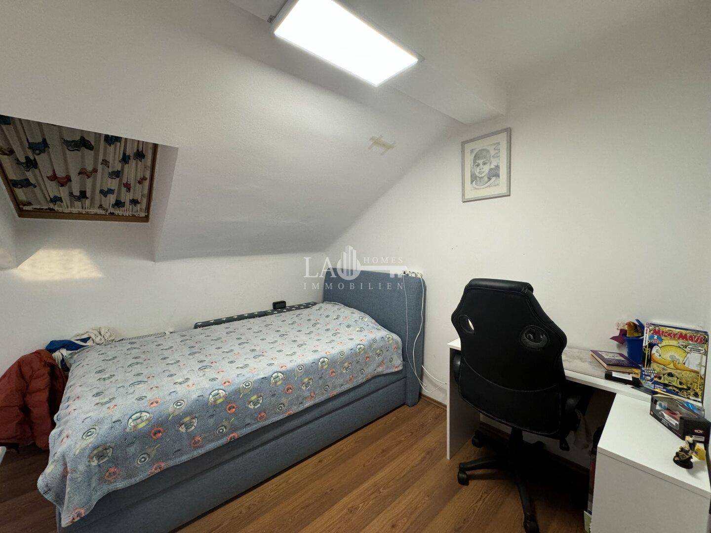 Kinderzimmer im Dachgeschoss mit Einzelbett, Schreibtisch und Dachfenster.
