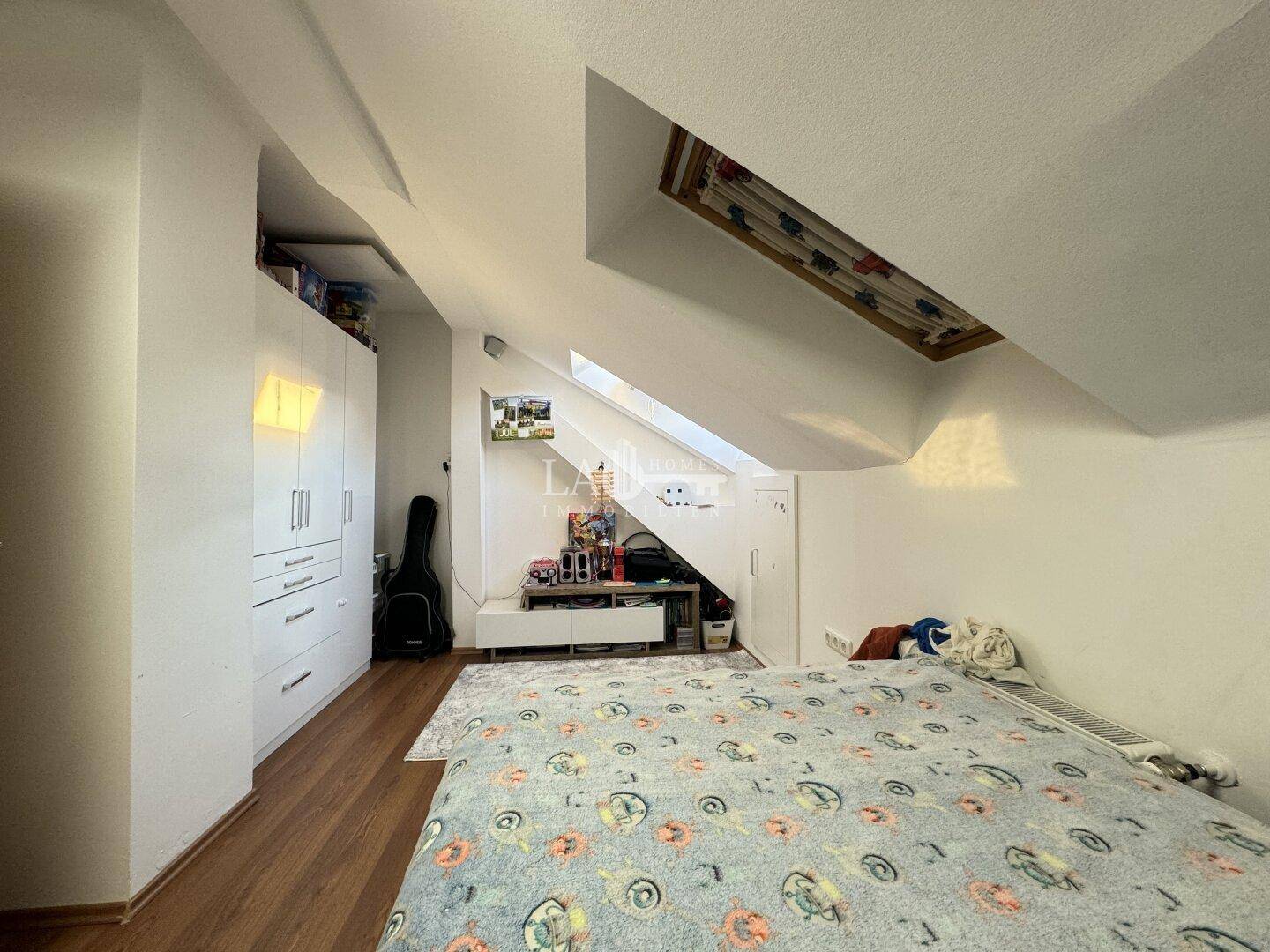 Kinderzimmer im Dachgeschoss mit Bett, Stauraum und Dachfenster.