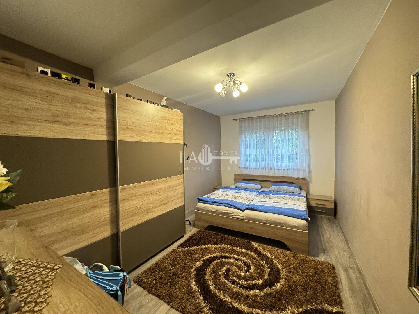 Gemütliches Schlafzimmer mit Doppelbett, Kleiderschrank und Teppich.