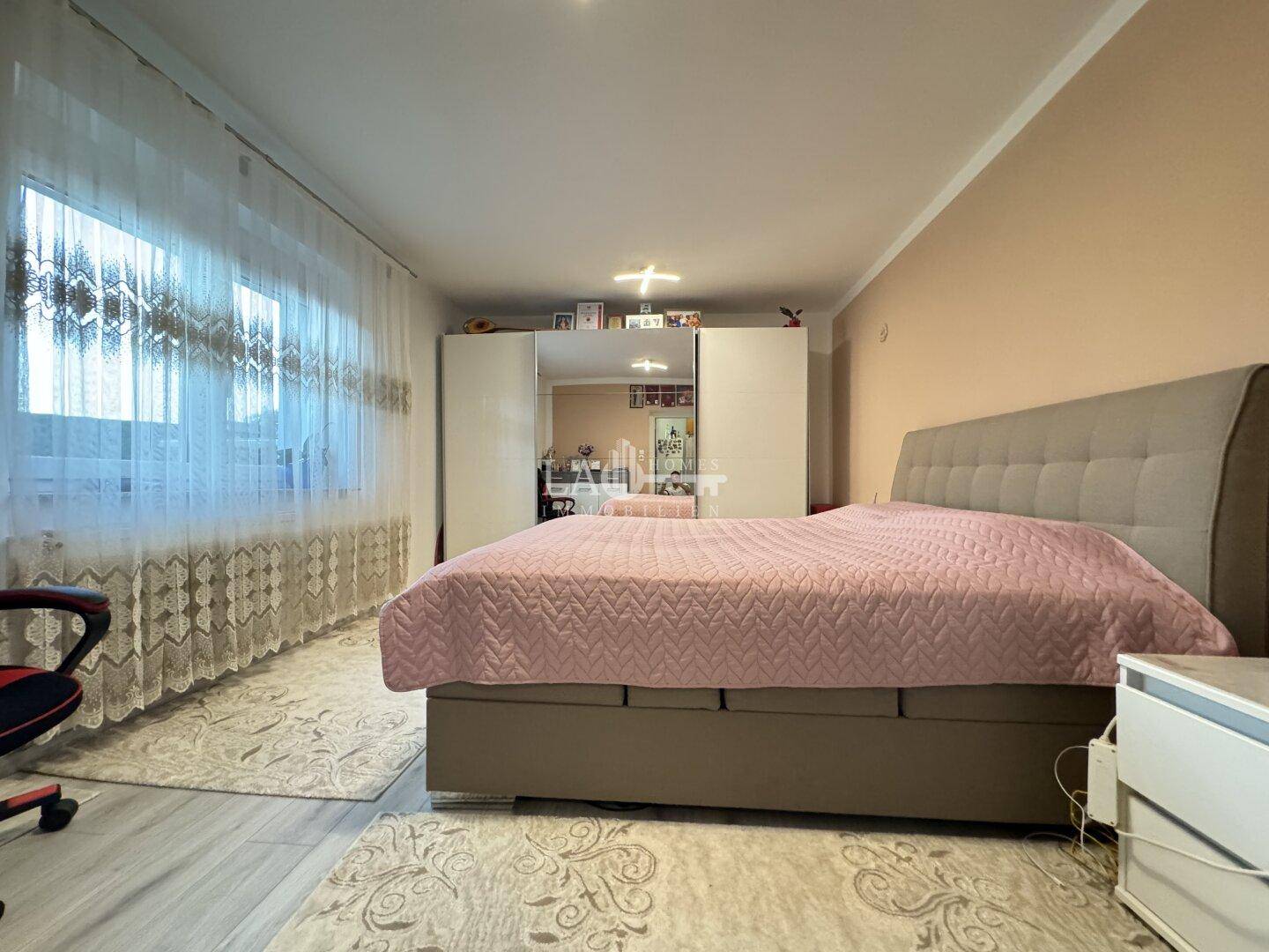 Geräumiges Schlafzimmer mit Doppelbett, Kleiderschrank und Teppich.